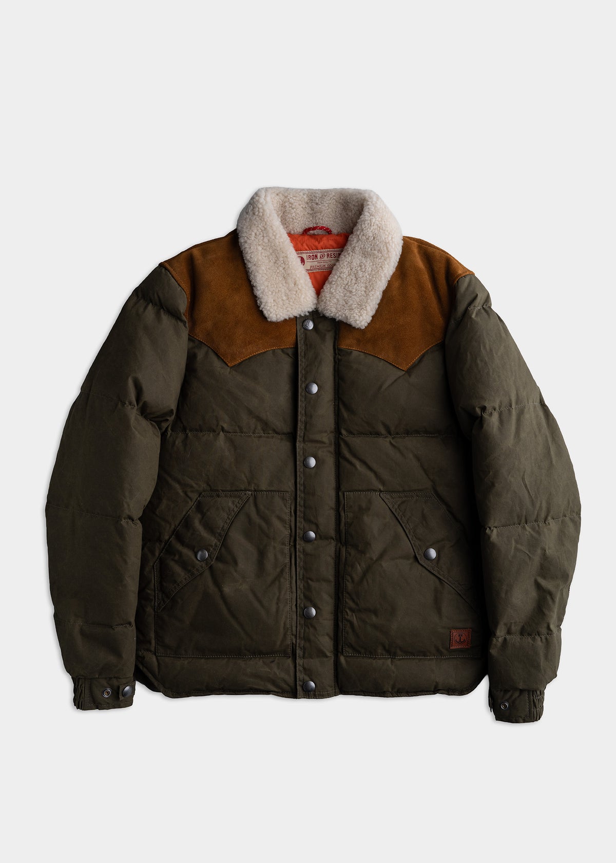 Olive green puffer jacket with brown suede yoke and cozy shearling collar, featuring snap buttons and large front pockets.