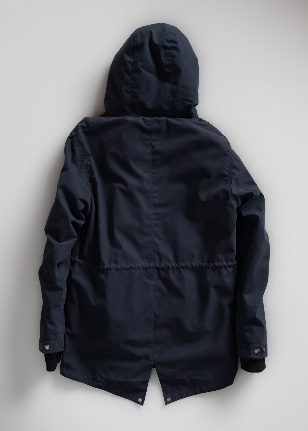Dark navy hooded jacket displayed flat on a light background, showcasing its back design and buttoned cuffs.