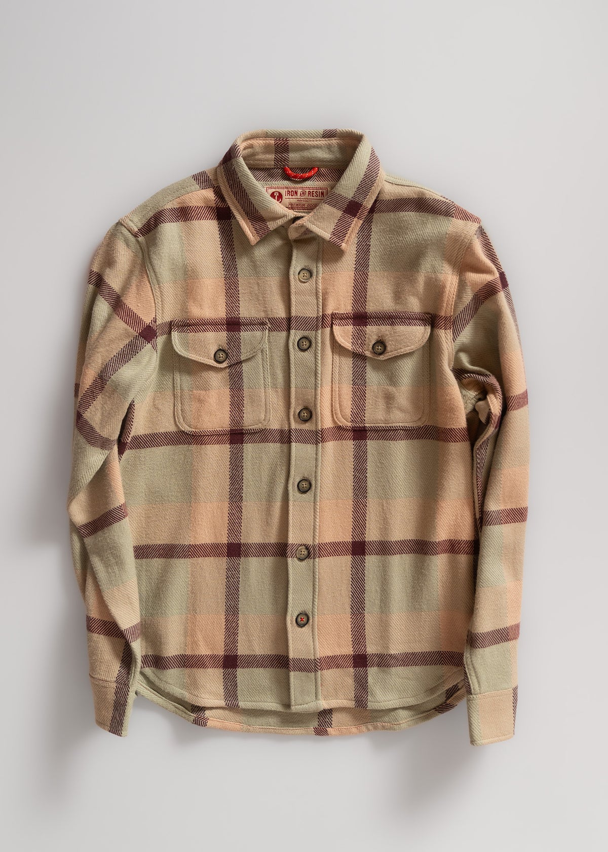 Beige and burgundy plaid flannel shirt with buttoned chest pockets, laid flat on a light surface, showcasing its classic design.