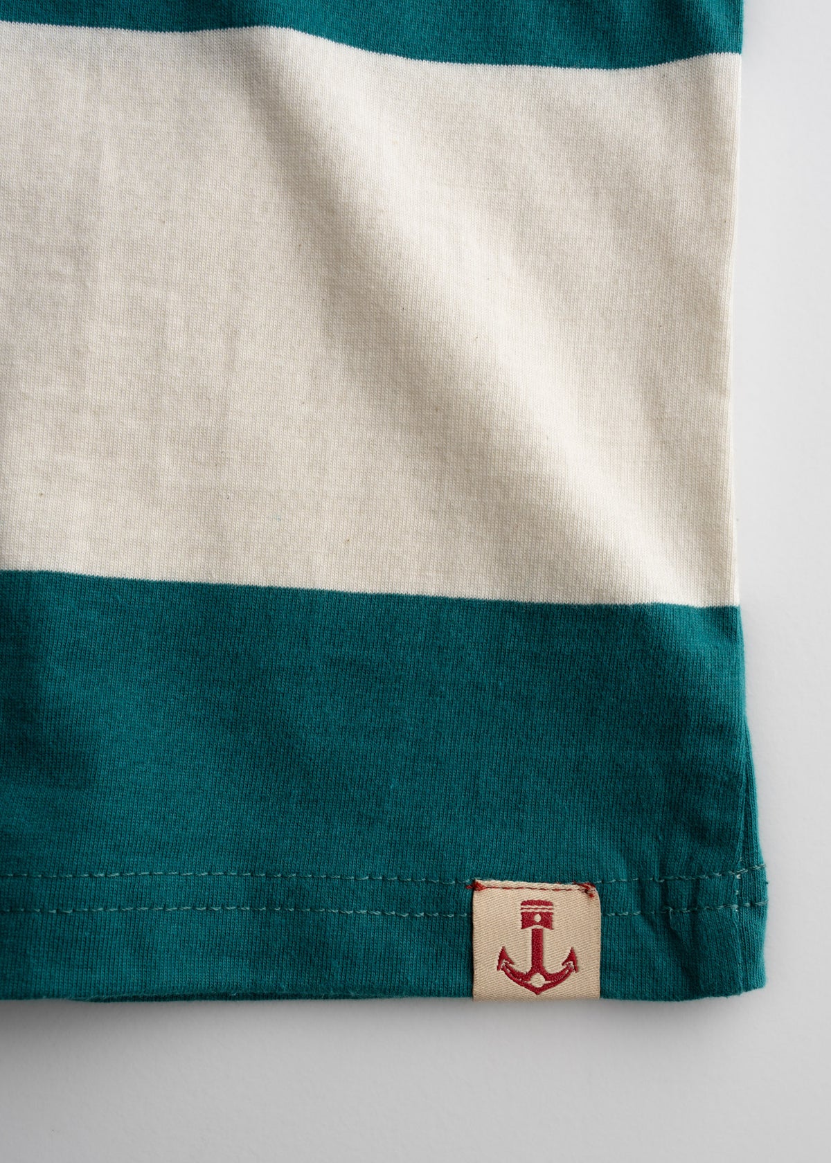 Close up of stripe pattern on cotton t-shirt, highlighting custom tag, color contrast and knit detail