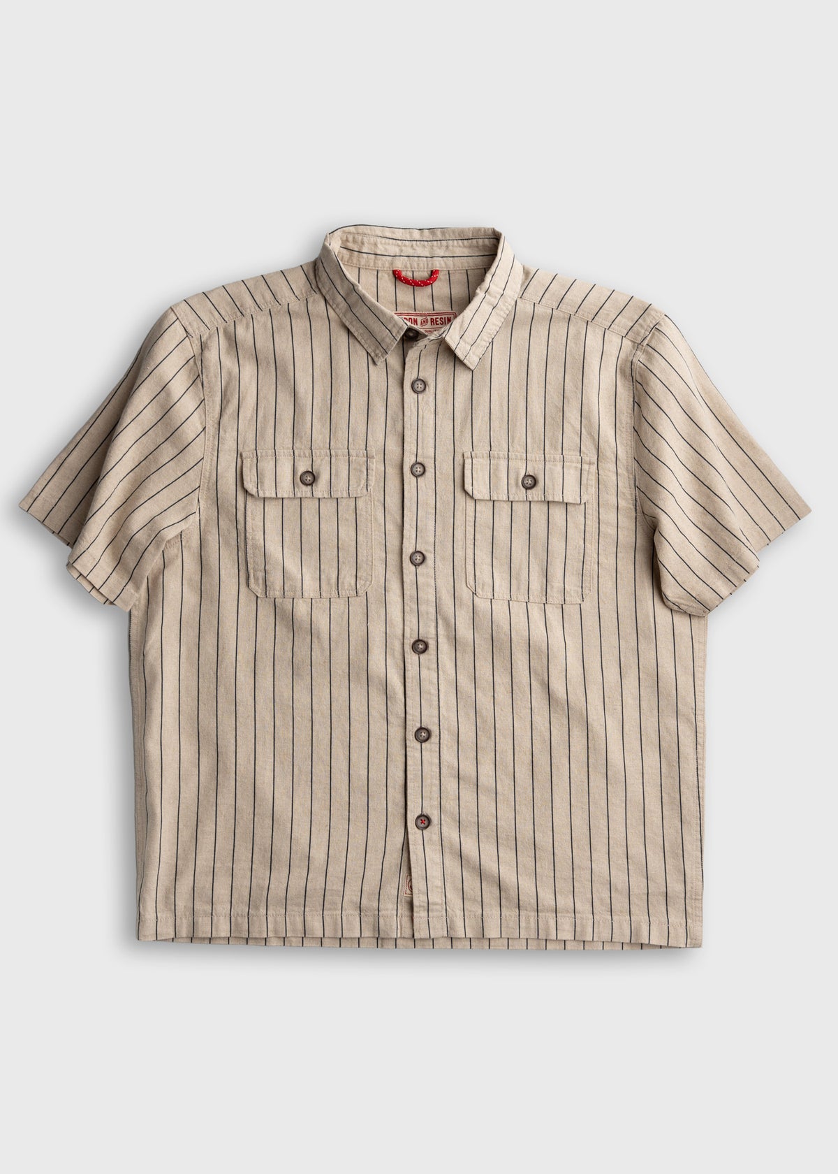 Beige short-sleeve shirt with vertical black stripes, button-up front, and two chest pockets, laid flat on a white background.