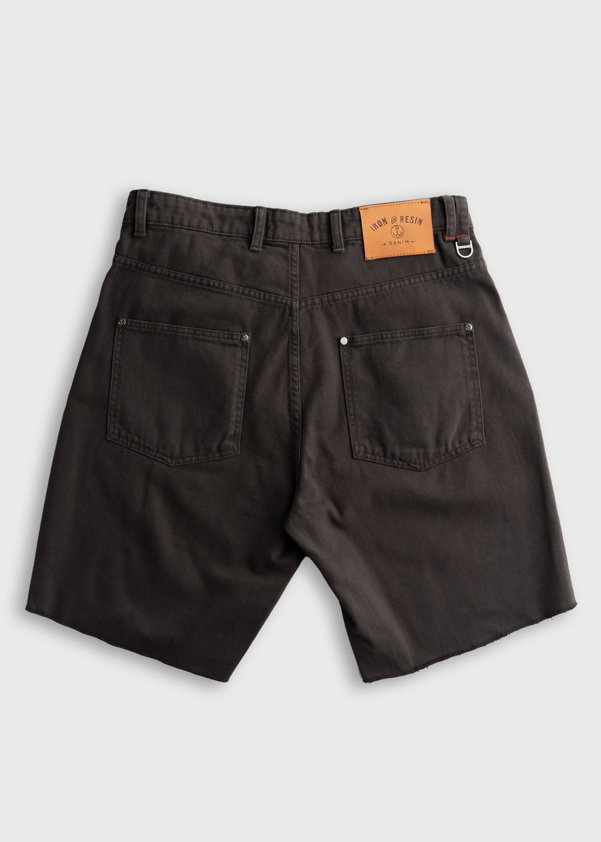 Dark shorts with back pockets, belt loops, and a brown Iron & Resin label on the waistband, displayed on a light background.