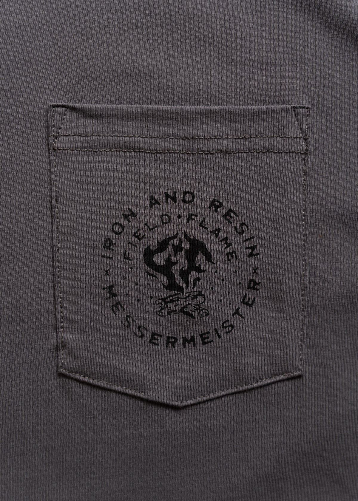 Gray shirt pocket with "Iron and Resin" logo featuring a campfire and the word "Messermeister" printed below.