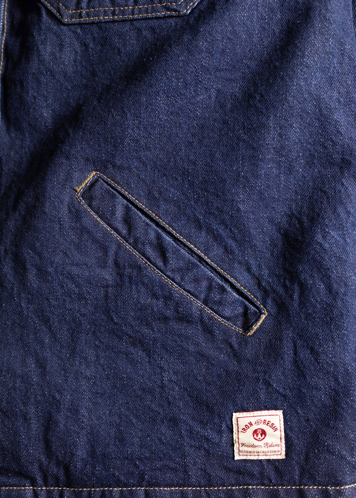 Denim fabric with a diagonal pocket and a small "Iron and Resin" label at the bottom, showcasing rugged style and craftsmanship.