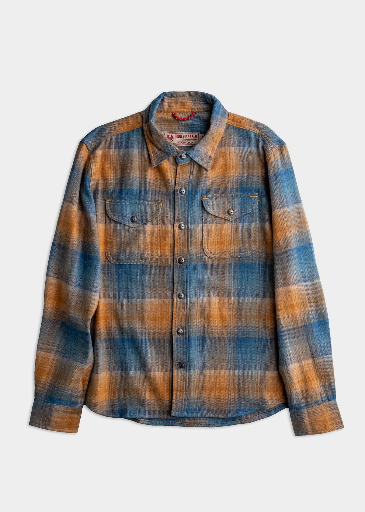Blue and orange plaid flannel shirt with buttoned front and chest pockets, laid flat on a white background.