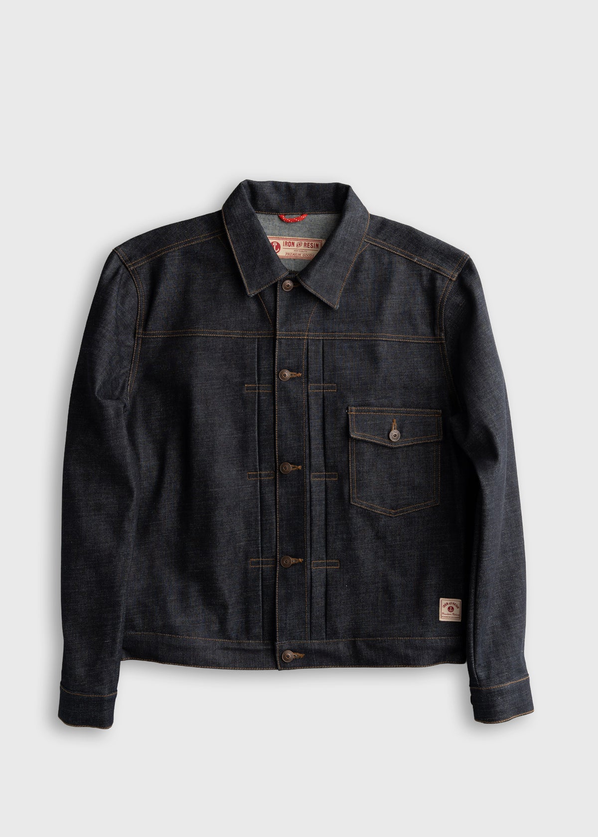 Dark denim jacket with brown stitching, buttoned front, and chest pocket. Features Iron & Resin label inside. Simple and stylish.