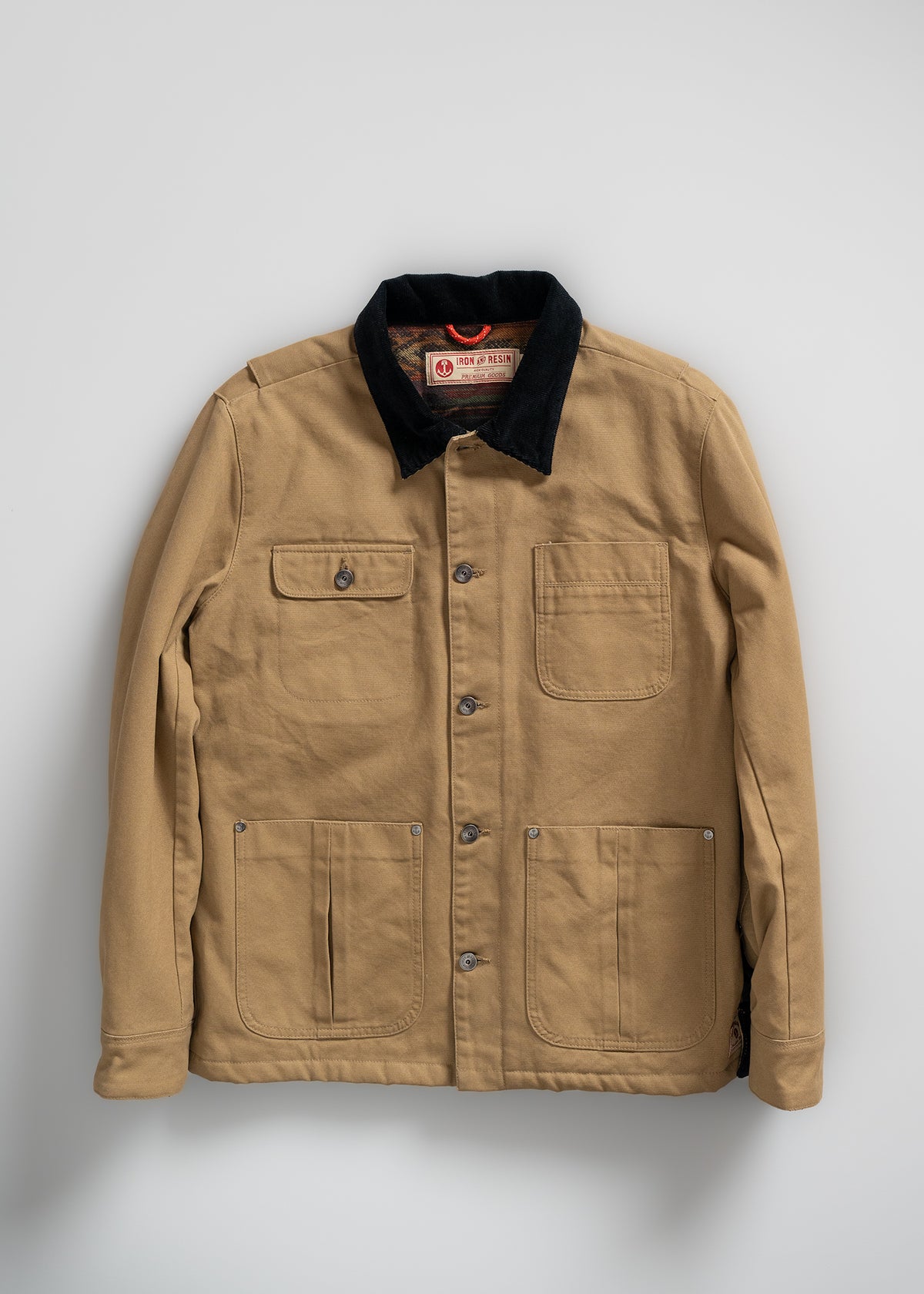 Tan canvas jacket with black corduroy collar, button front, and three pockets, displayed on a light gray background.