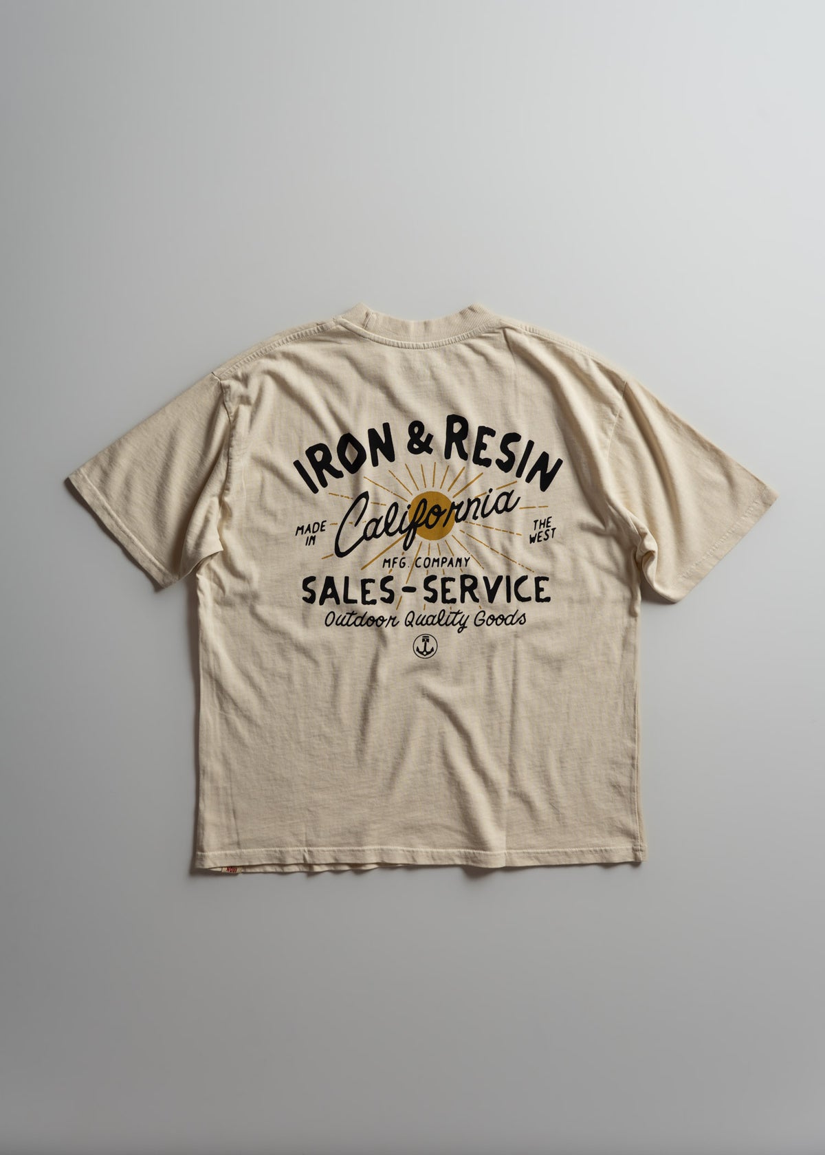 Beige T-shirt with "Iron & Resin, California" text, featuring outdoor quality goods design, laid flat on a gray background.