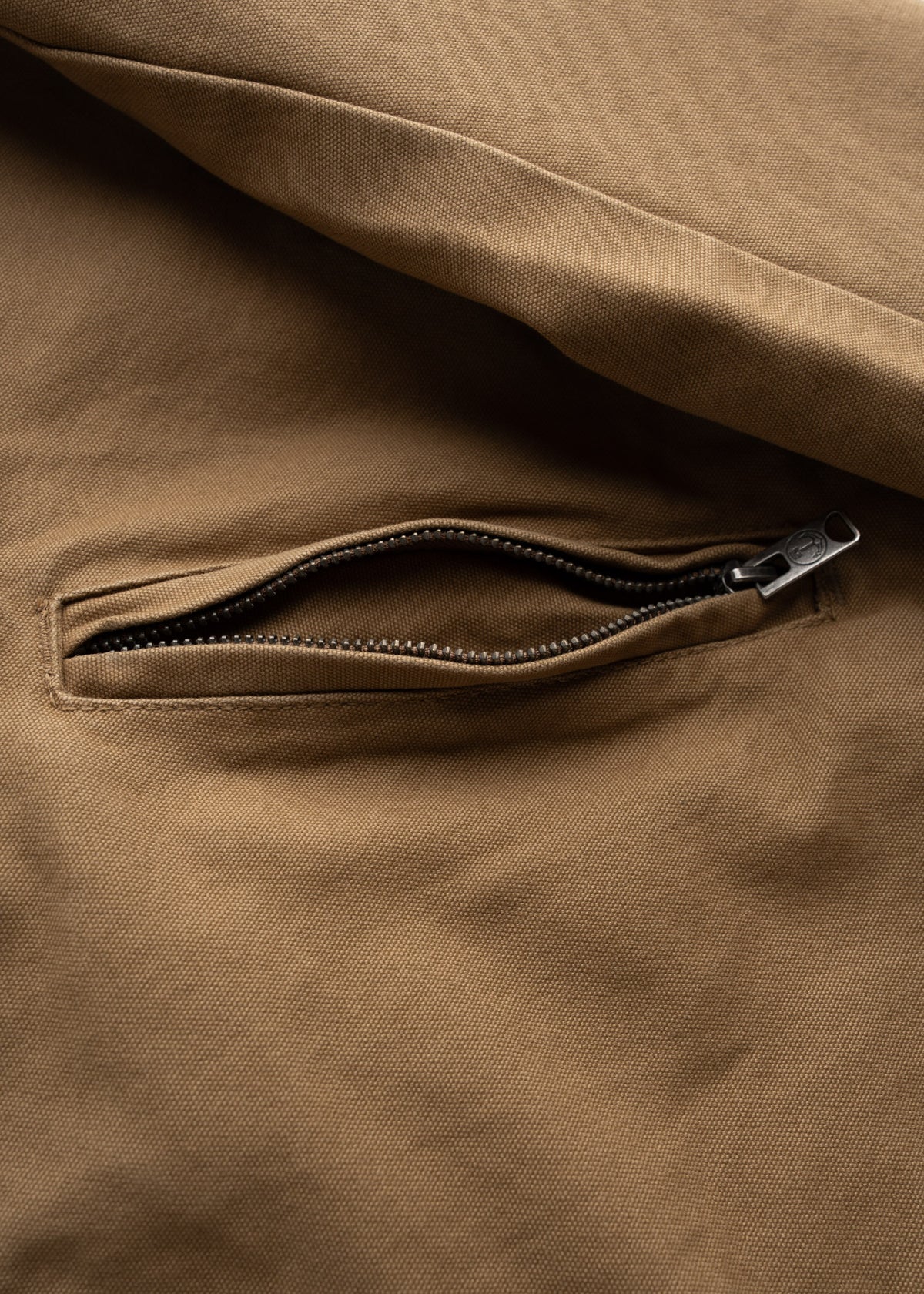 Close-up of a brown fabric with a partially open zipper pocket, revealing the texture and stitching details.