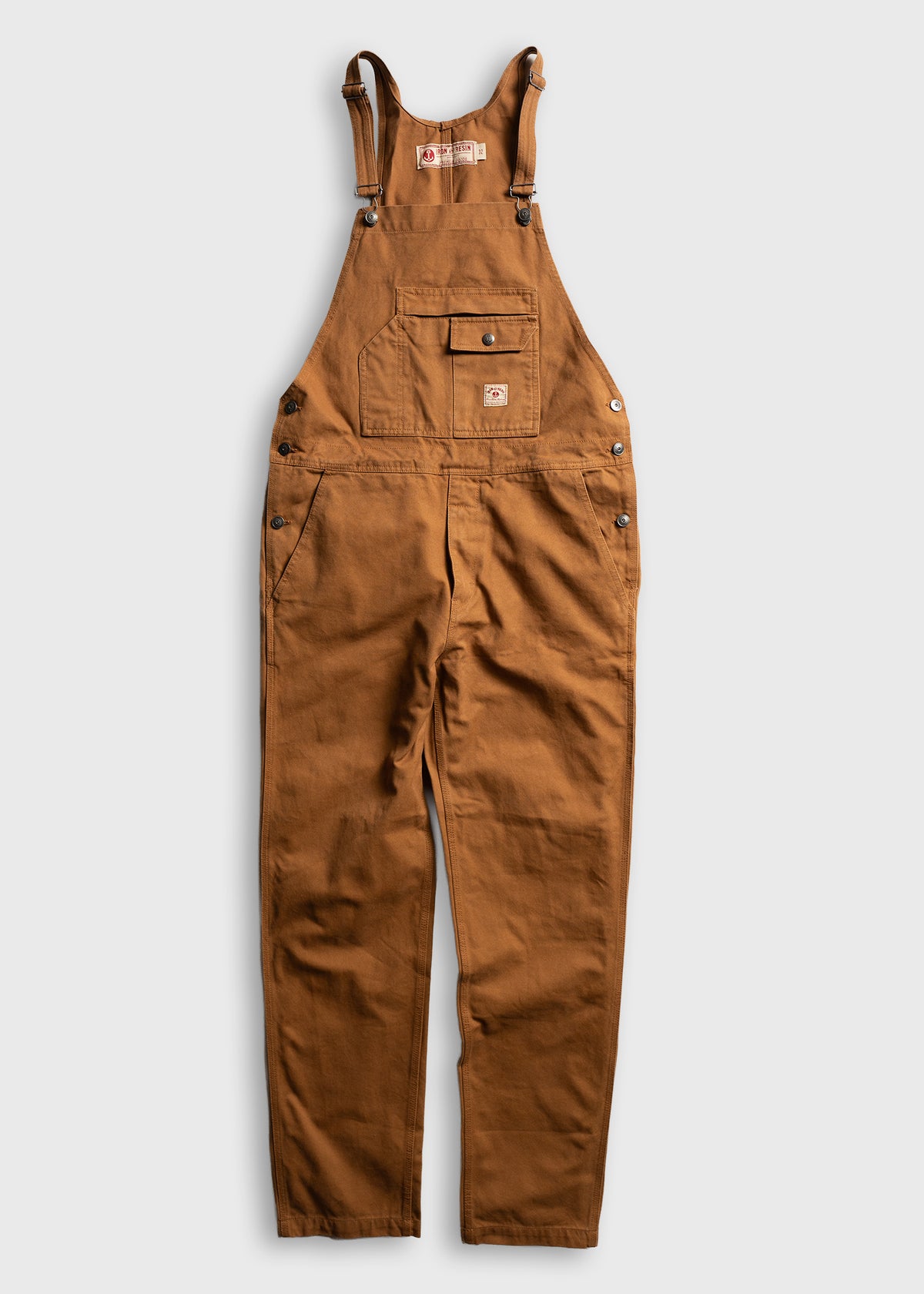 Brown work overalls with adjustable straps, front pocket, and button details, laid flat on a light background.