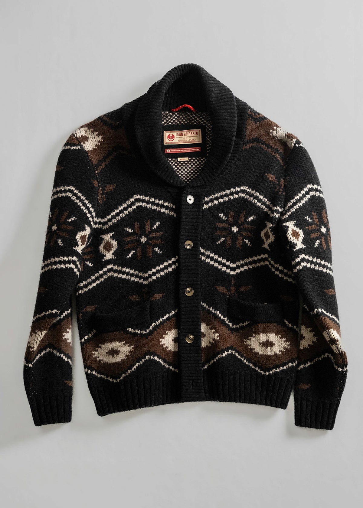 Black shawl collar cardigan with brown and white geometric patterns, buttoned front, and two pockets on a plain background.