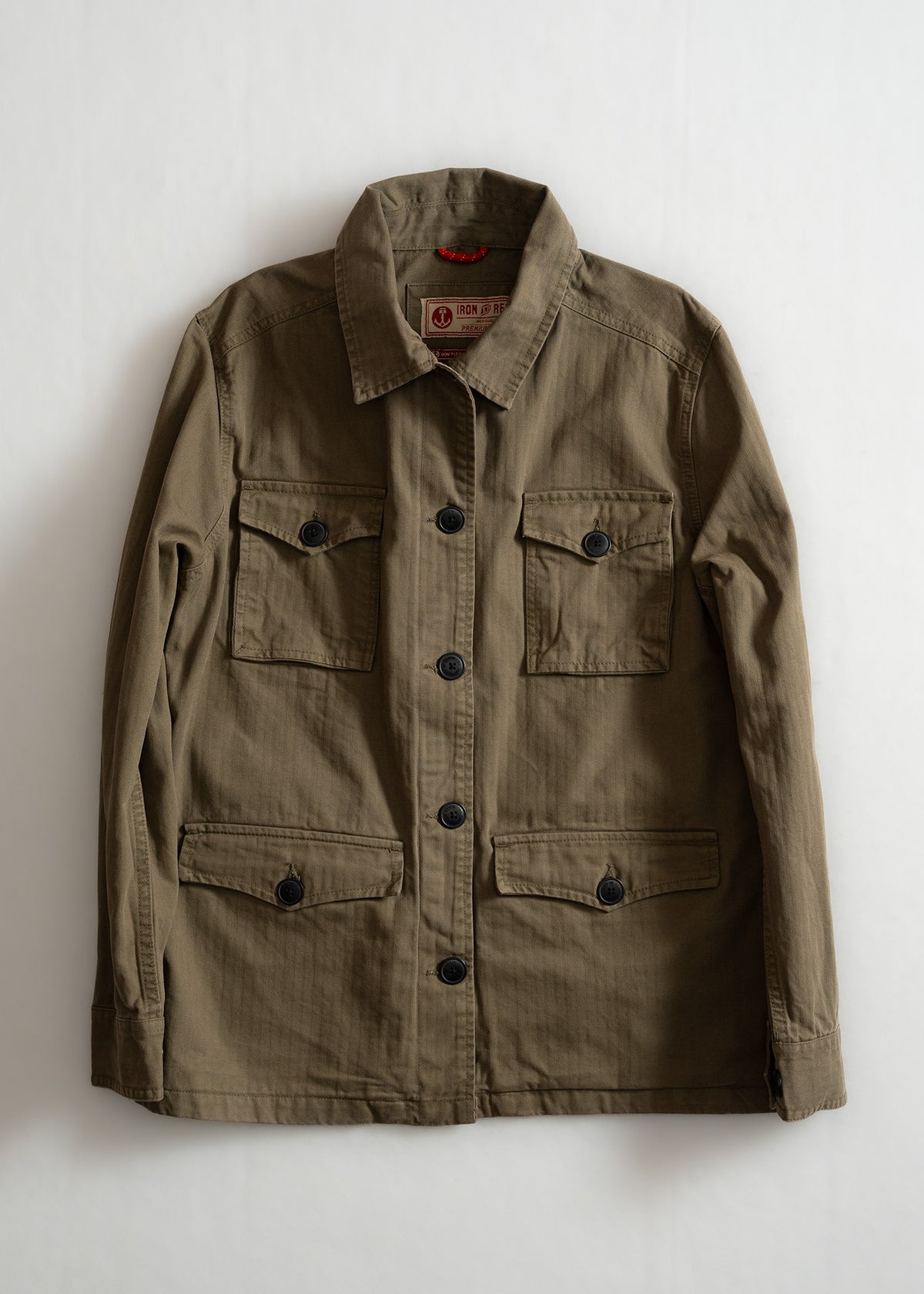 Khaki jacket with black buttons and four pockets, laid flat on a white background. Simple, classic design for versatile wear.