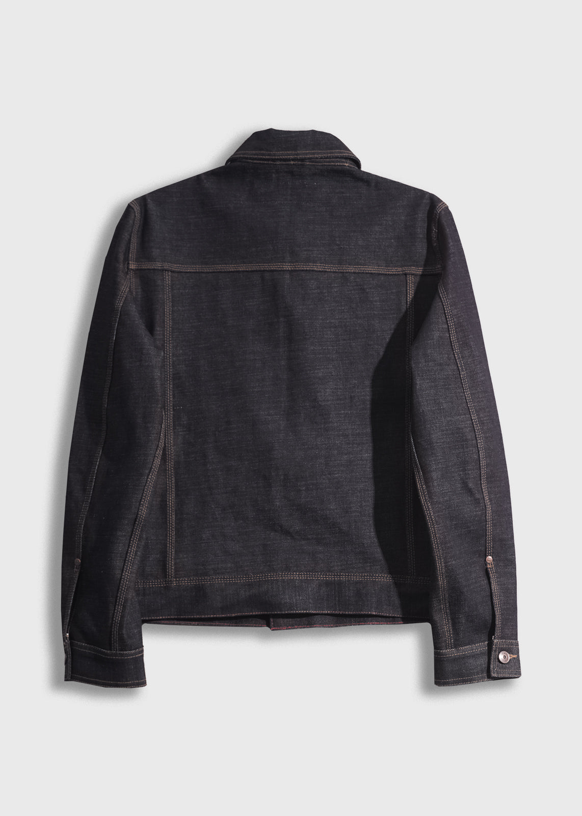 Back view of a dark denim jacket with visible stitching, buttoned cuffs, and a classic collar, set against a plain background.