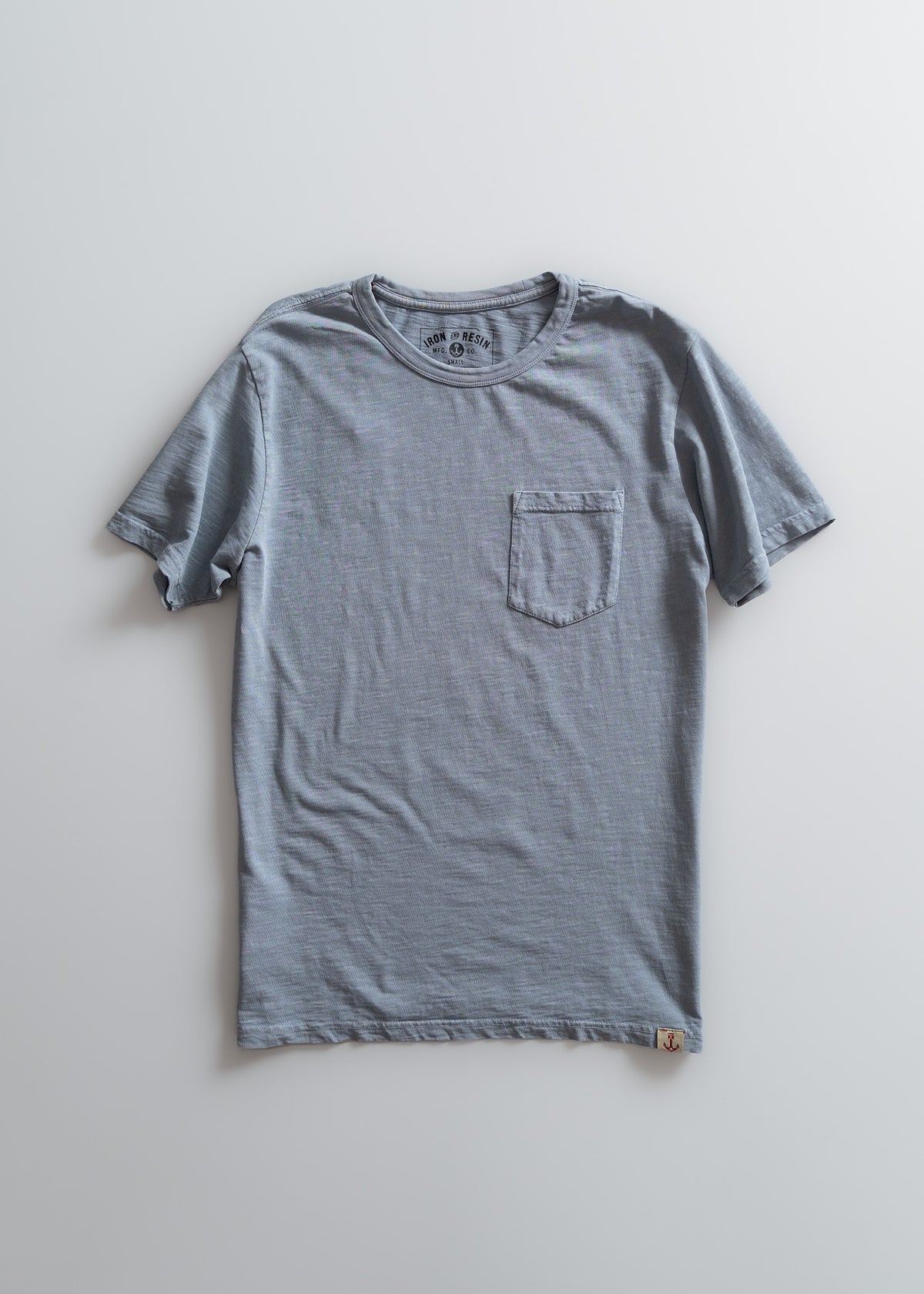 Gray T-shirt with a chest pocket on a light background, featuring a subtle texture and a small logo tag at the hem.