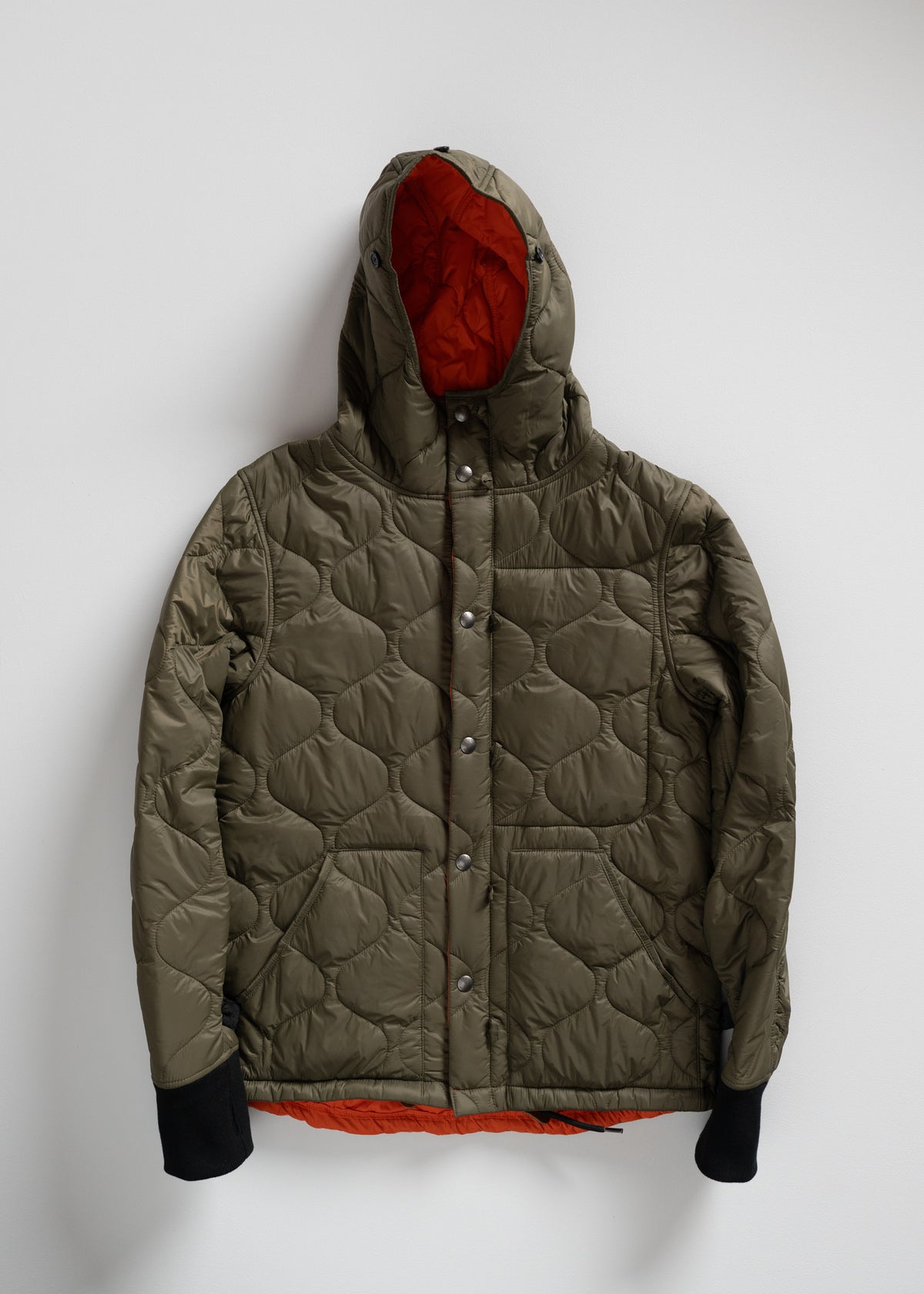 Olive quilted jacket with a hood and orange lining, featuring black cuffs and button closure, displayed against a white background.