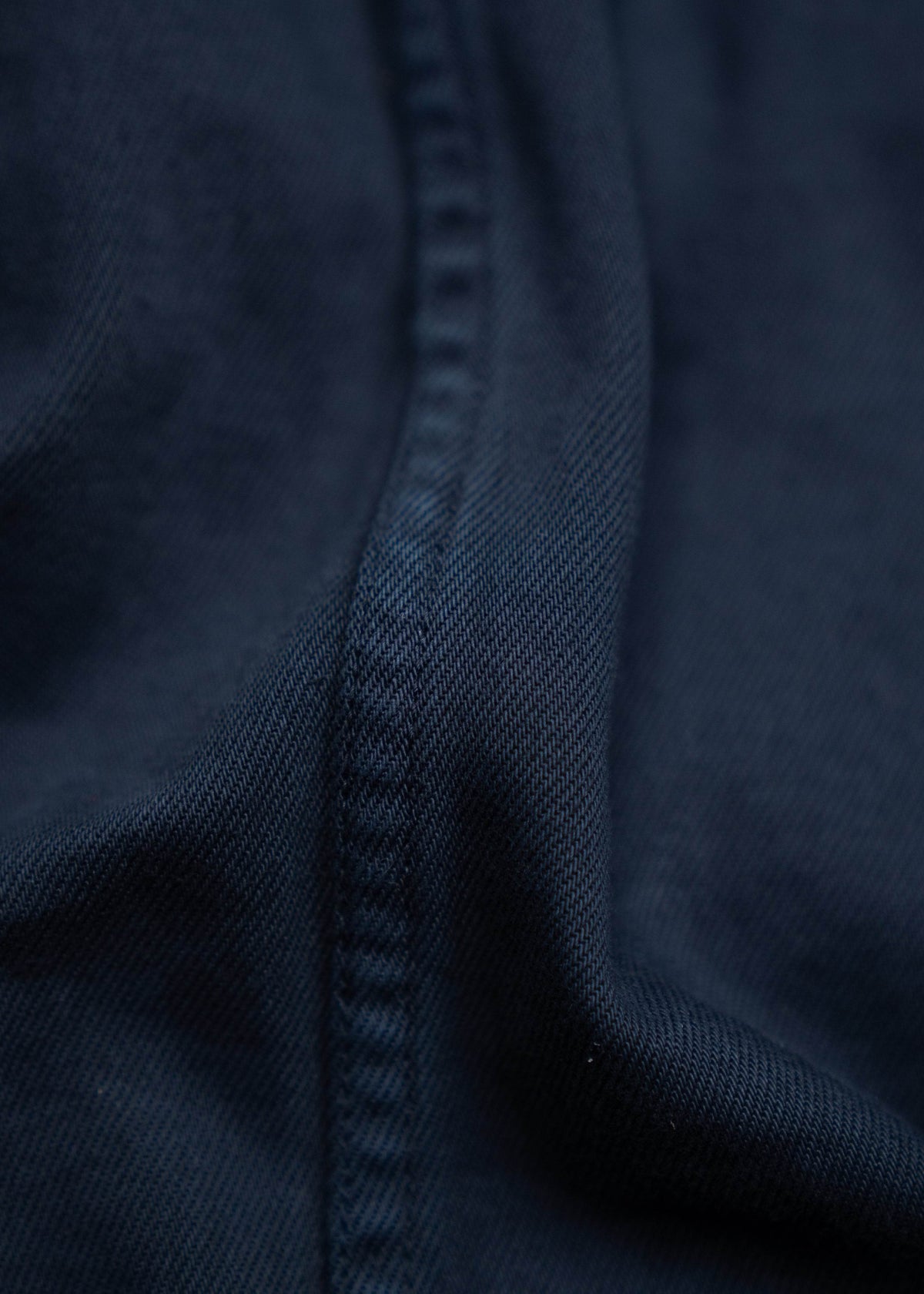 Close-up of dark blue fabric with visible seam, showcasing texture and stitching detail.