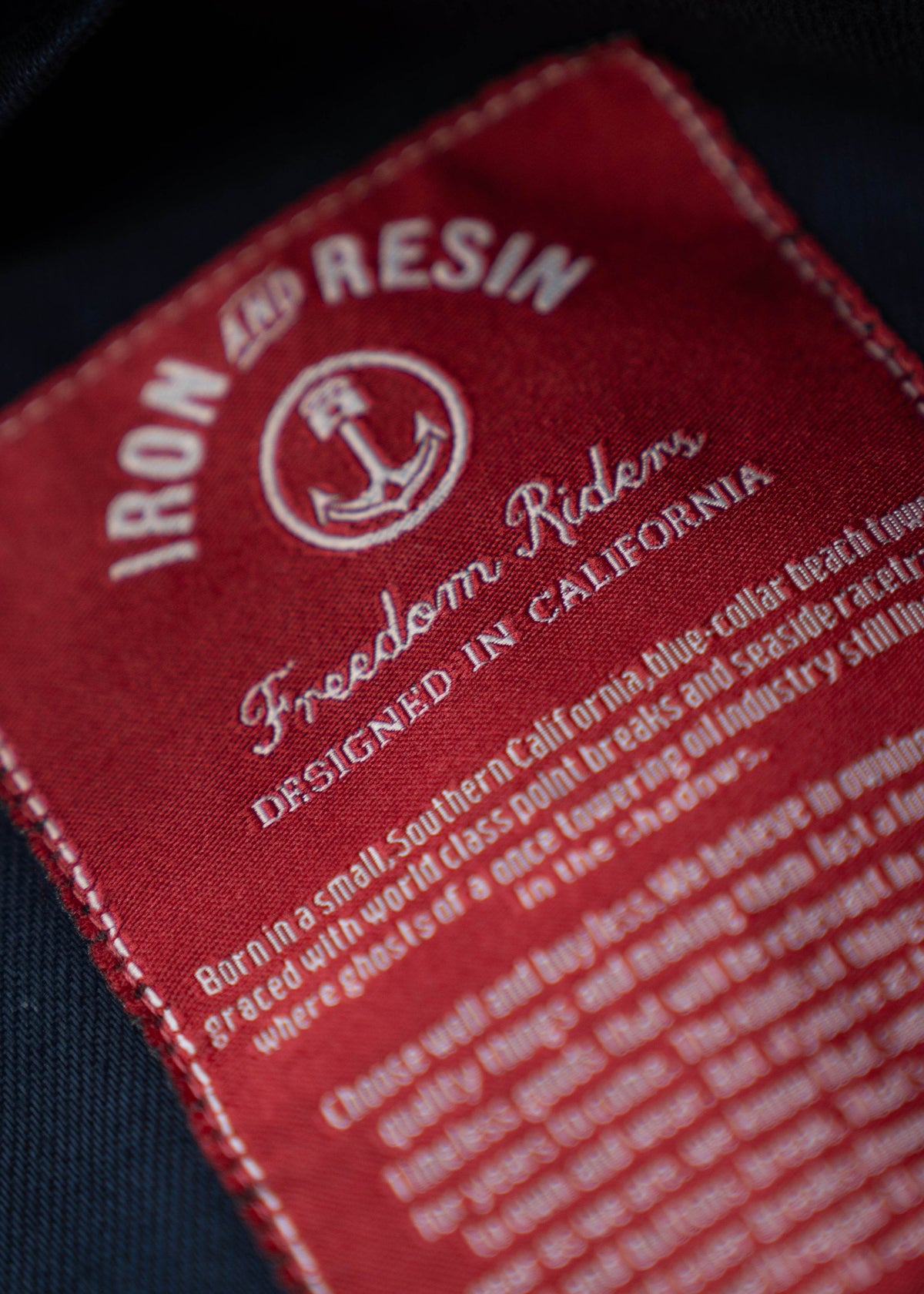 Close-up of a red "Iron and Resin" label with an anchor logo, reading "Freedom Riders, Designed in California."