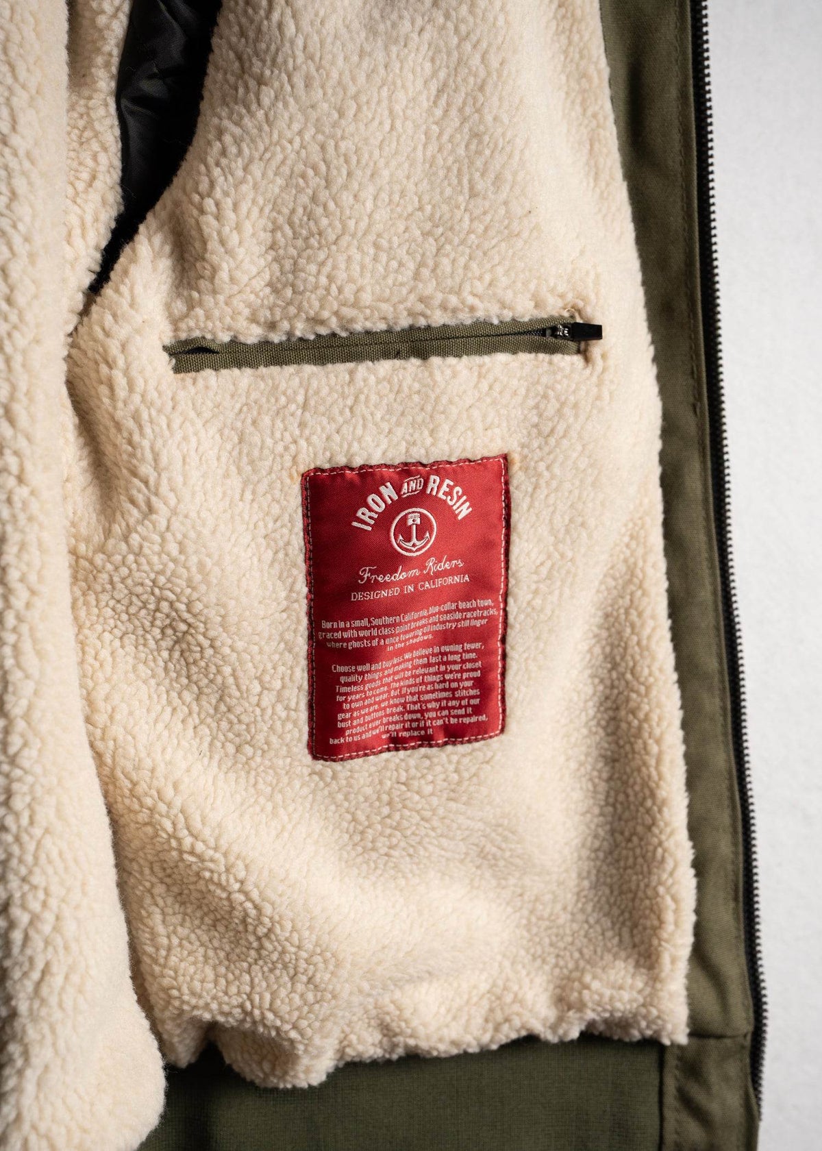 Fleece jacket interior with a red "Iron and Resin" label and a zippered pocket, showcasing cozy design and craftsmanship details.