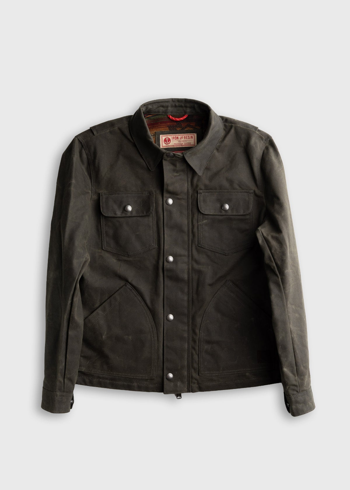 Dark green waxed canvas jacket with snap buttons, two chest pockets, and a collar, labeled "Iron and Resin" inside.