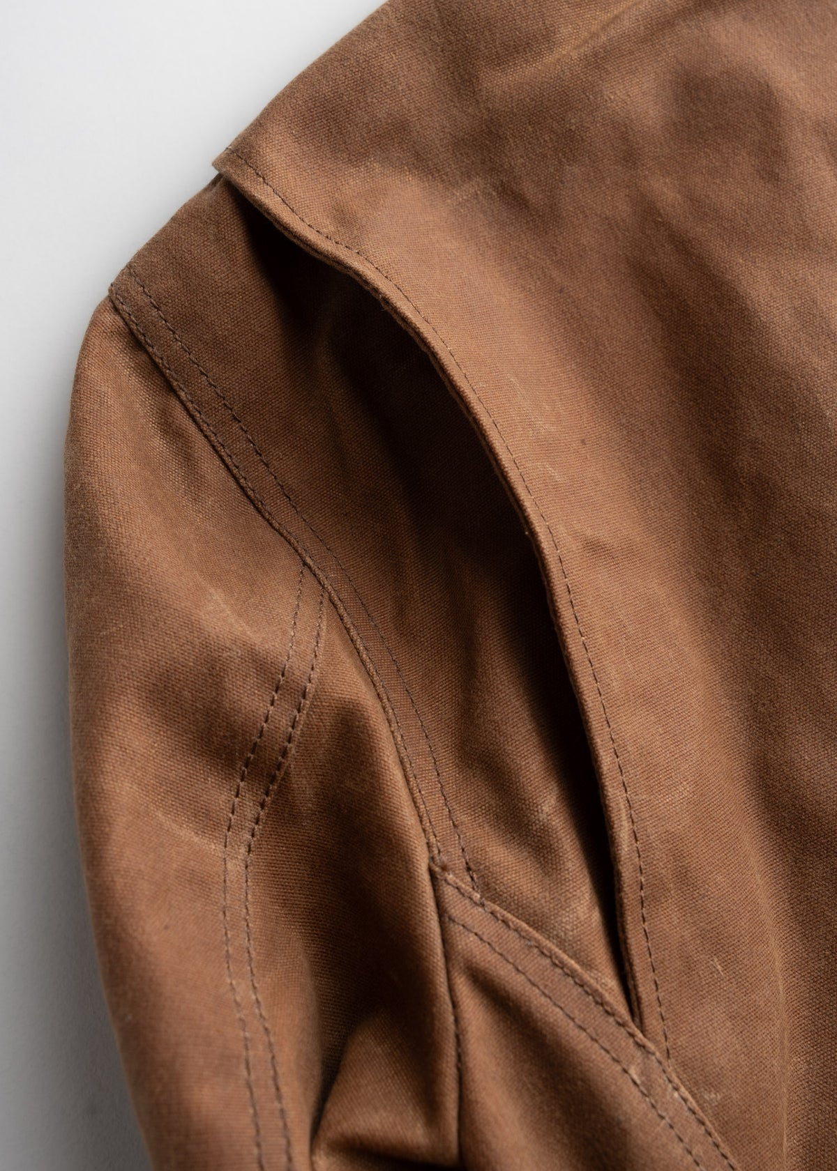 Close-up of brown fabric with visible stitching and seam details, highlighting texture and craftsmanship.