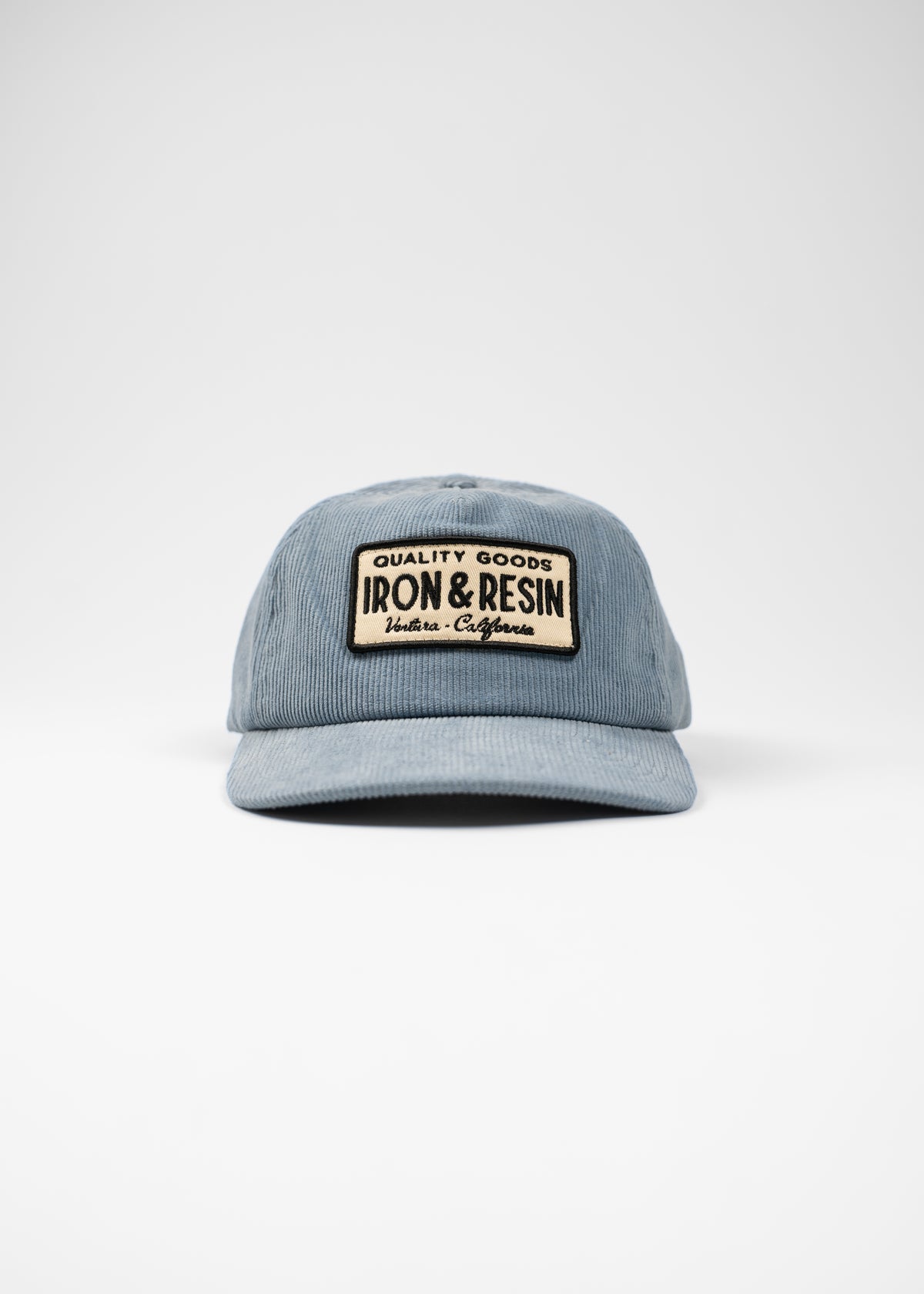 Blue corduroy cap with "Iron & Resin" patch, highlighting quality goods from Ventura, California, on a plain white background.