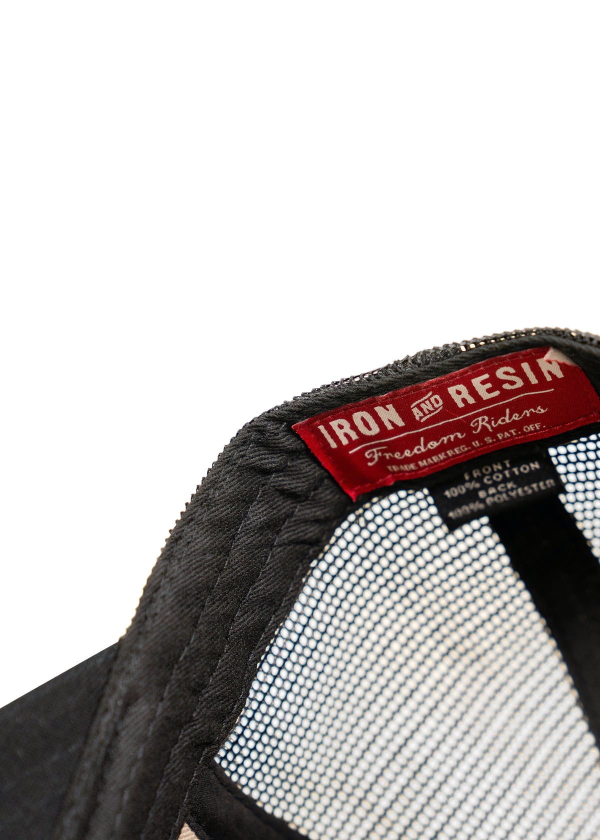 Close-up of a black cap's interior label reading "Iron and Resin Freedom Riders," with mesh lining visible.