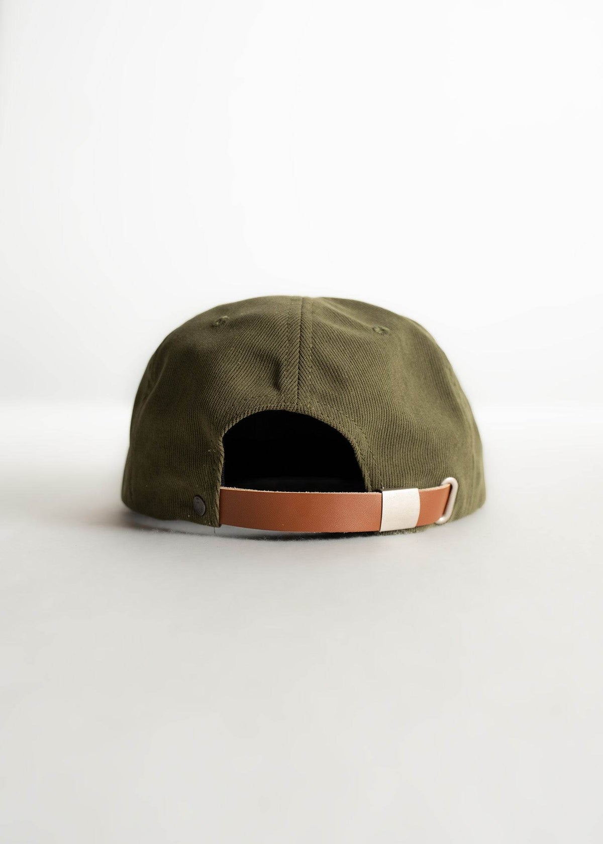 A green baseball cap with a brown leather strap is shown from the back on a white background.