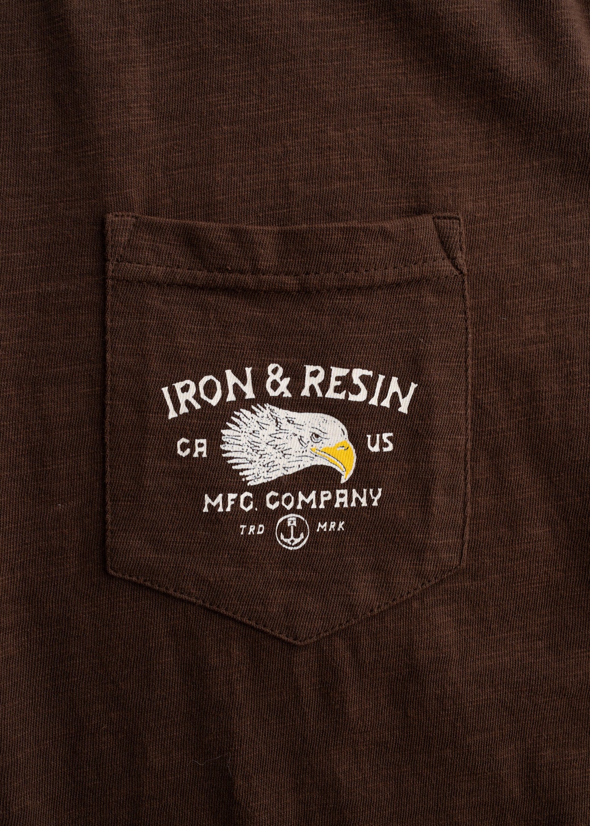 Men’s 7.5 oz organic combed cotton Brown t-shirt with custom graphic print and soft feel, lightweight everyday tee, close-up shot detailing fabric, chest pocket and graphic