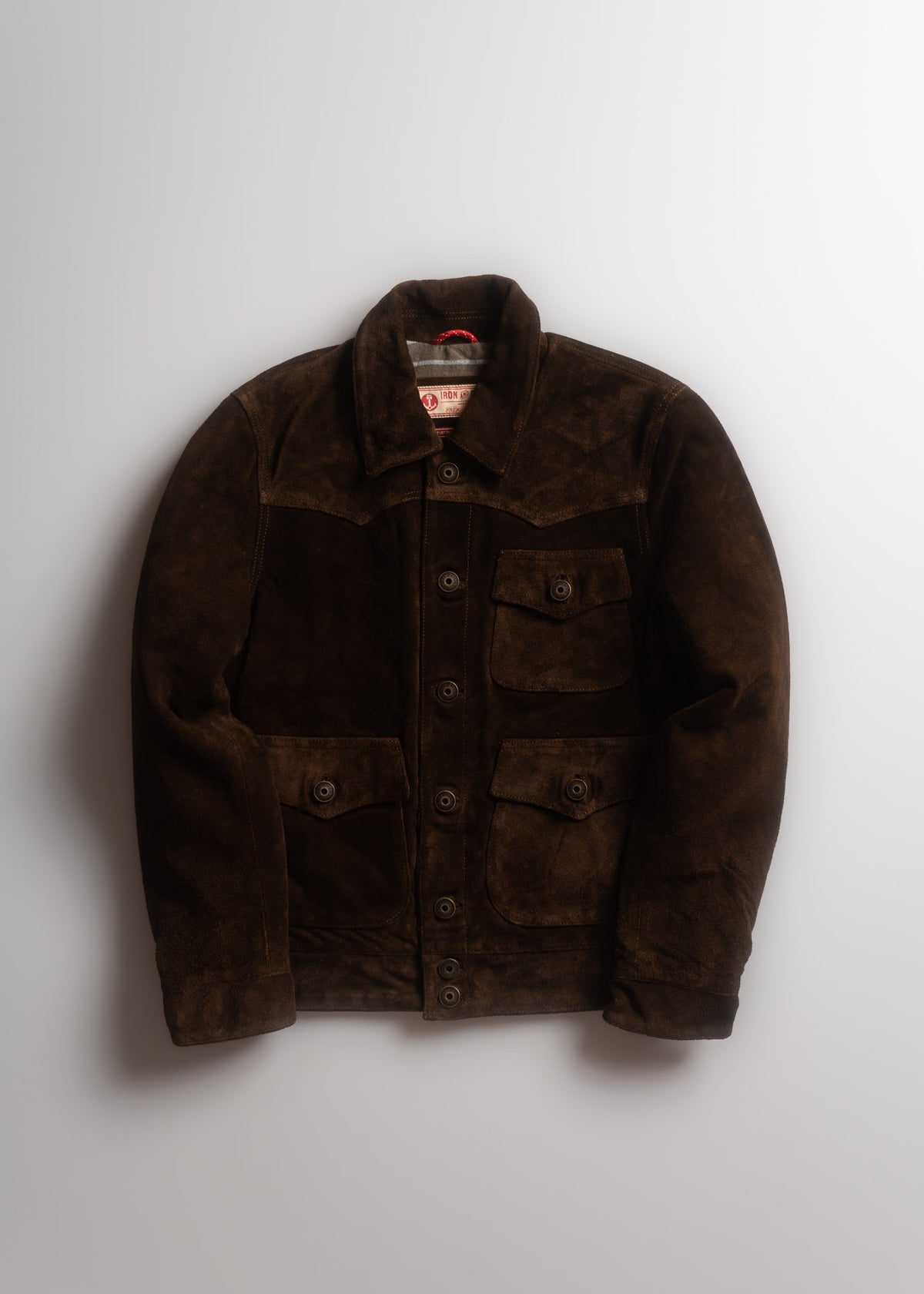 Brown suede jacket with button closure and four pockets, displayed on a white background.