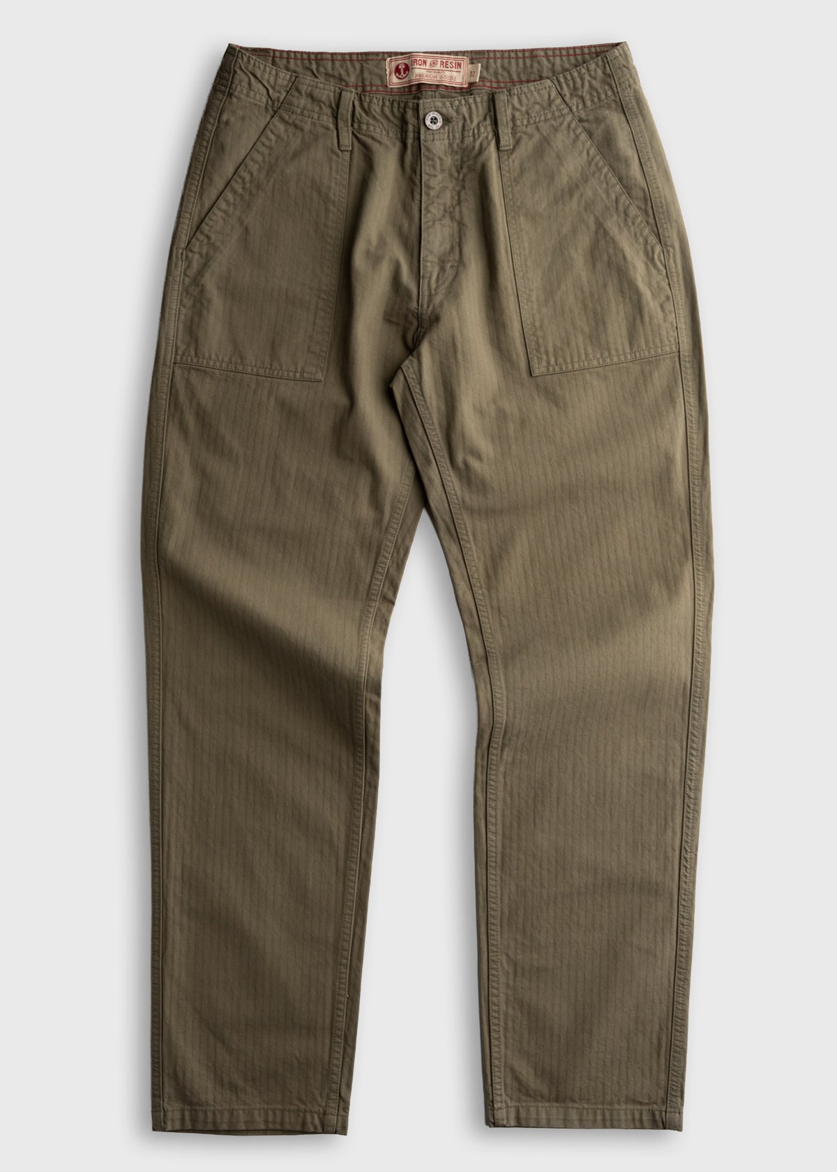 Olive green pants with front pockets and button closure, laid flat on a white background. Iron & Resin label visible inside.