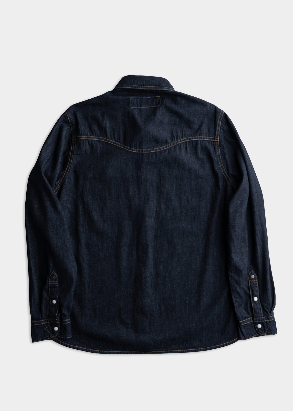 Dark denim shirt with long sleeves, back view. Features contrast stitching and buttoned cuffs on a plain white background.