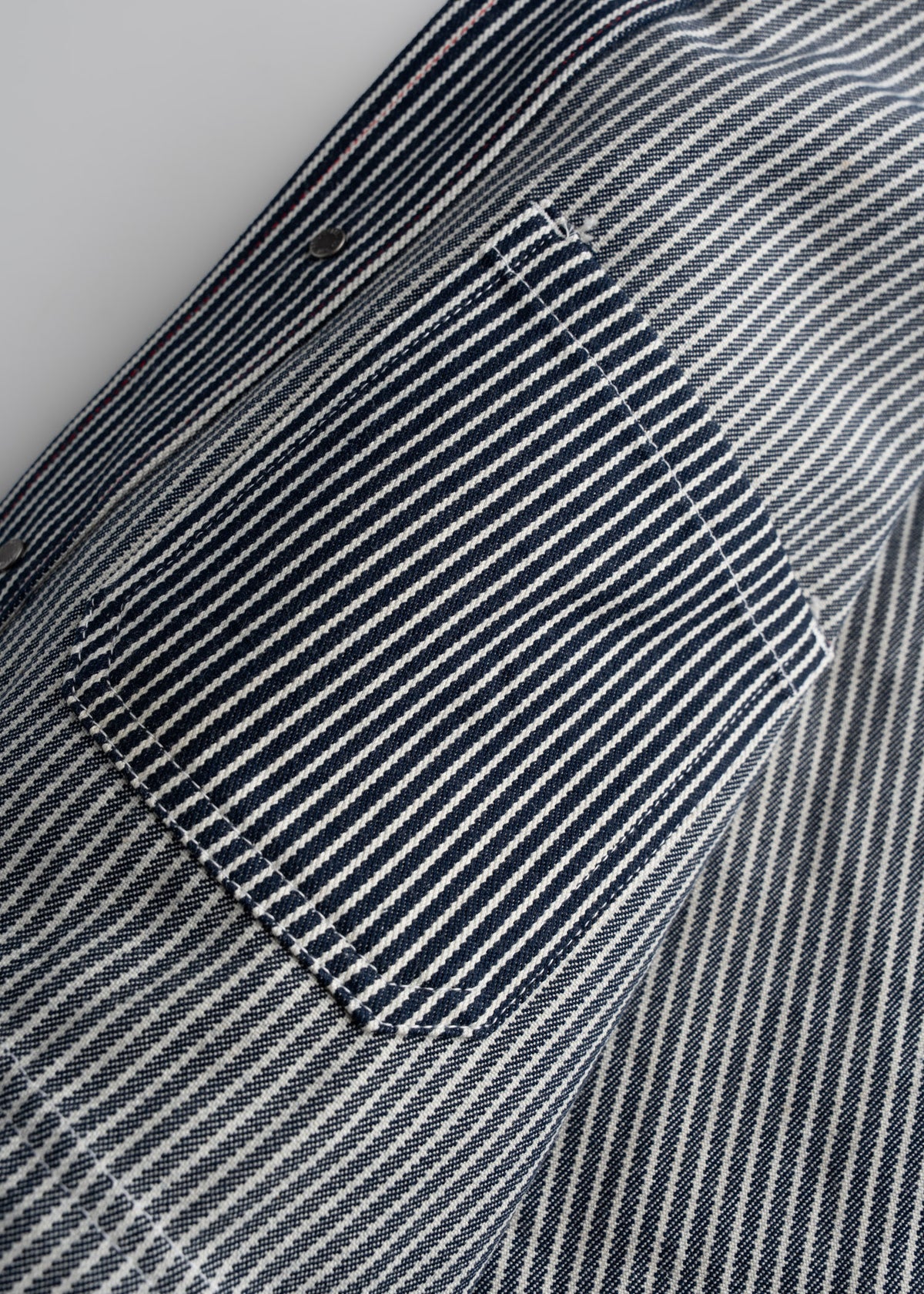 Close-up of a blue and white striped fabric with a pocket, showcasing detailed stitching and texture.