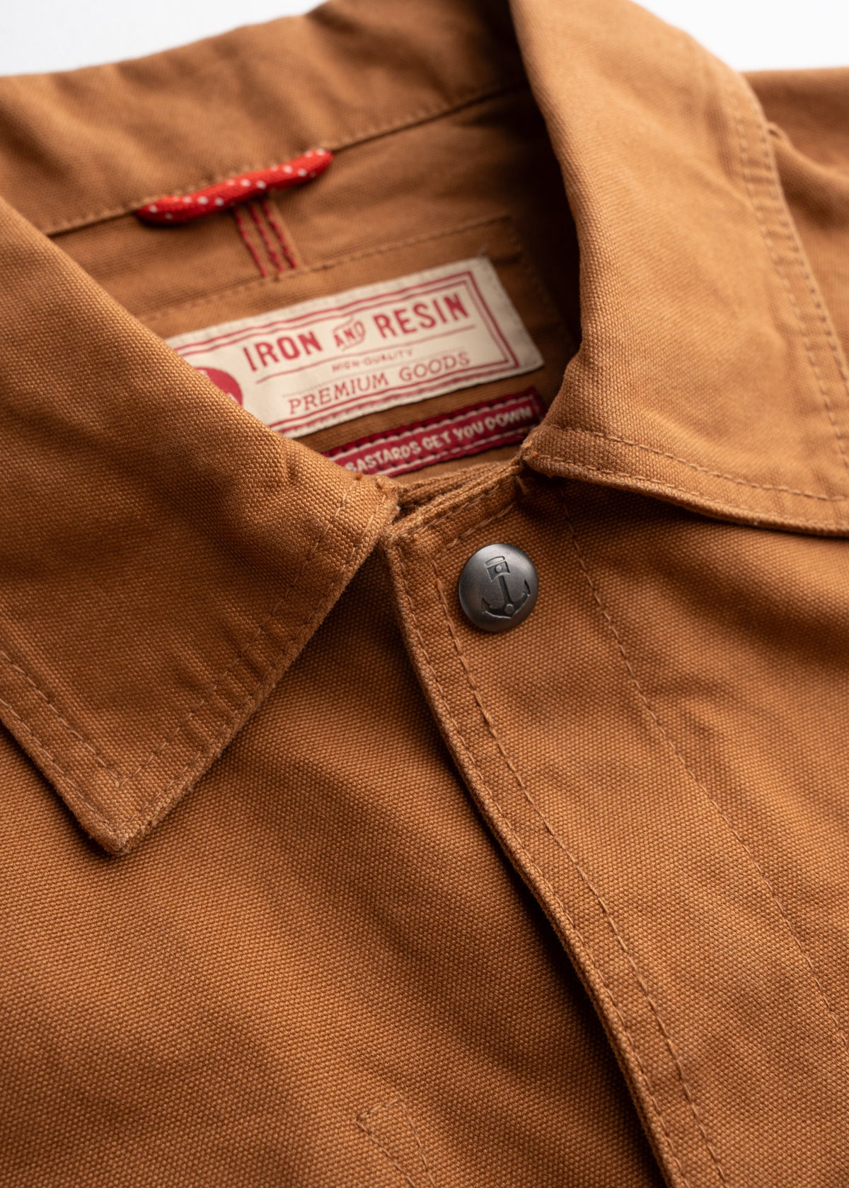 Close-up of a brown Iron and Resin jacket collar with a visible label and button, showcasing premium craftsmanship and style.