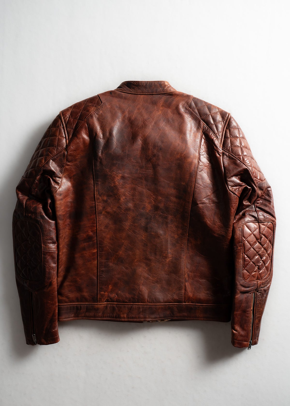Brown leather jacket with quilted sleeves, back view. The rich texture and stitching detail enhance its rugged, stylish appeal.