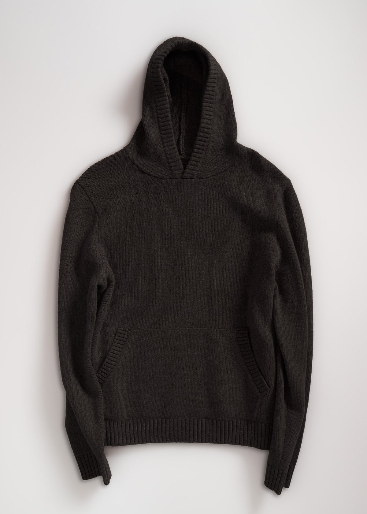 Dark gray knit hoodie with ribbed cuffs and hem, featuring a front pocket. Laid flat on a light background. Cozy and stylish.