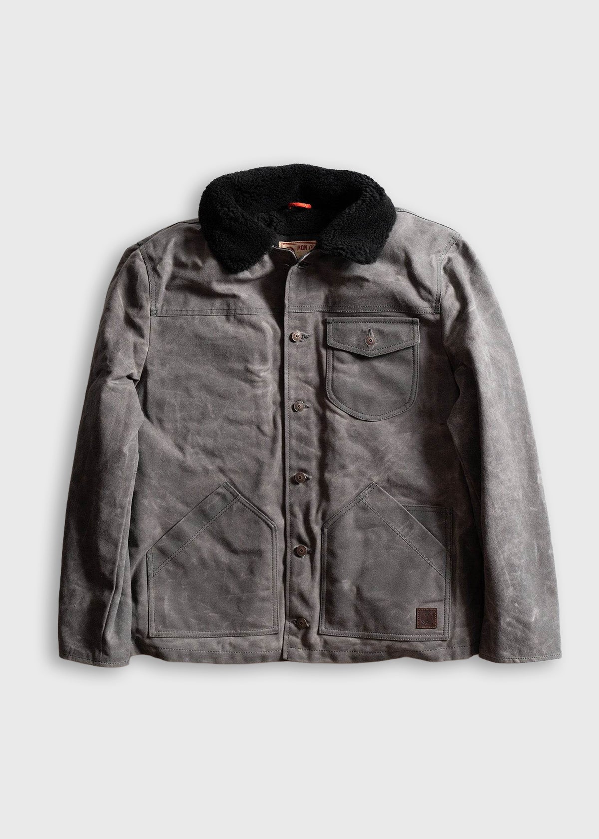 Gray waxed canvas jacket with black sherpa collar, button closure, and multiple pockets, displayed on a plain background.