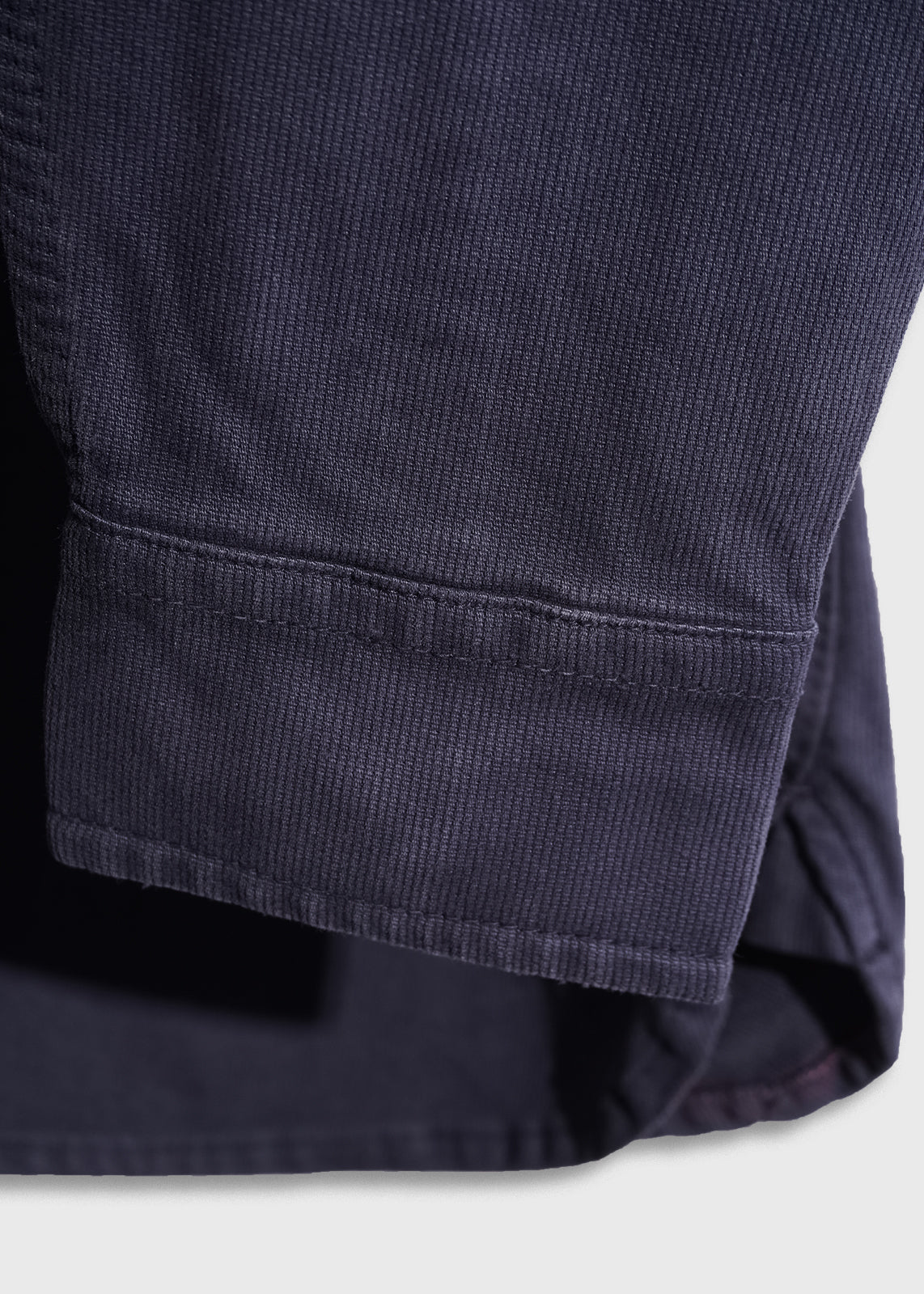 Close-up of a navy blue corduroy fabric sleeve, showcasing its texture and stitching detail against a light background.