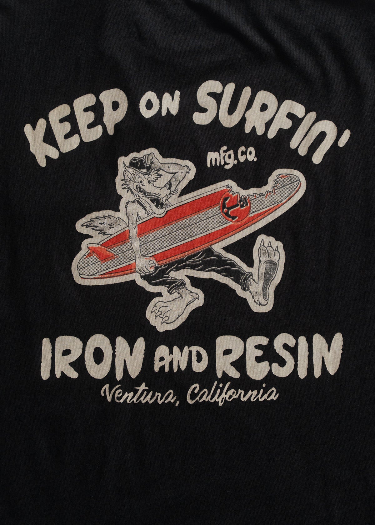 Cartoon wolf with surfboard on black shirt. Text: "Keep on Surfin', Iron and Resin, Ventura, California."