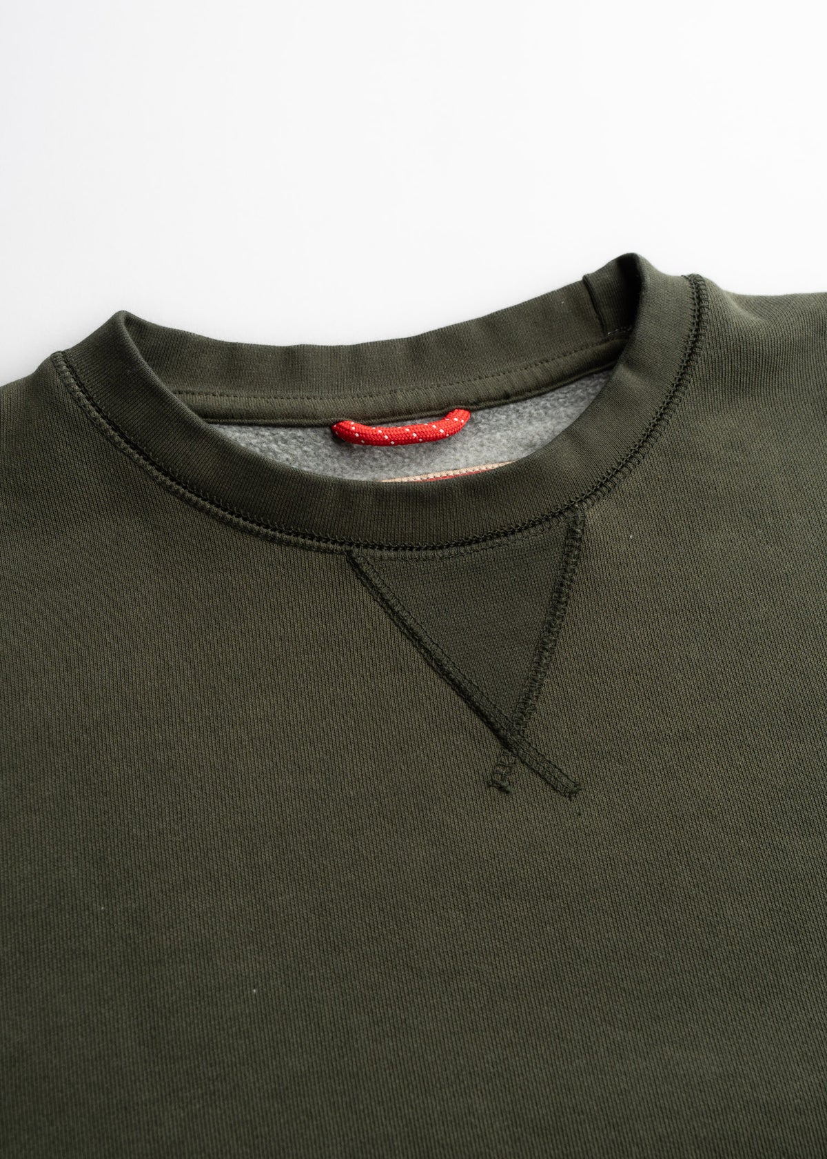 Dark green sweatshirt with a red neck loop and V-stitch detail on a white background, showcasing simple and classic design.