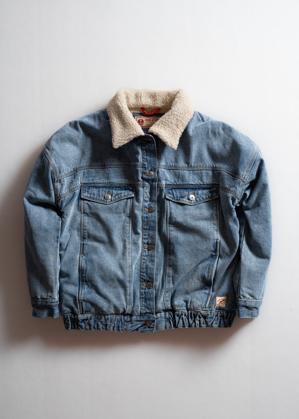 Denim jacket with a cozy shearling collar, buttoned front, and two chest pockets, displayed against a plain white background.