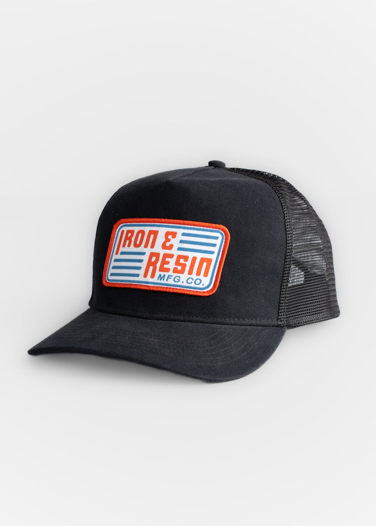 Black trucker hat with "Iron & Resin MFG. CO." patch in red and blue on front, featuring mesh back and curved brim.