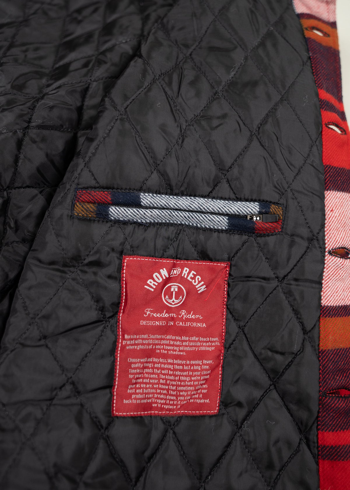 Quilted black jacket interior with red Iron and Resin label, plaid trim, and text about California design and quality values.