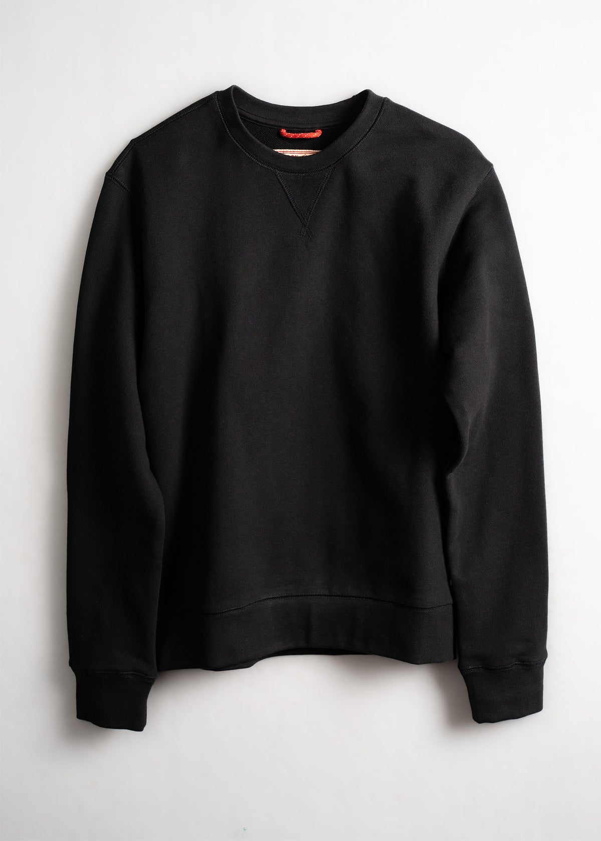 A black crewneck sweatshirt with long sleeves is displayed against a plain white background, showcasing its simple design.
