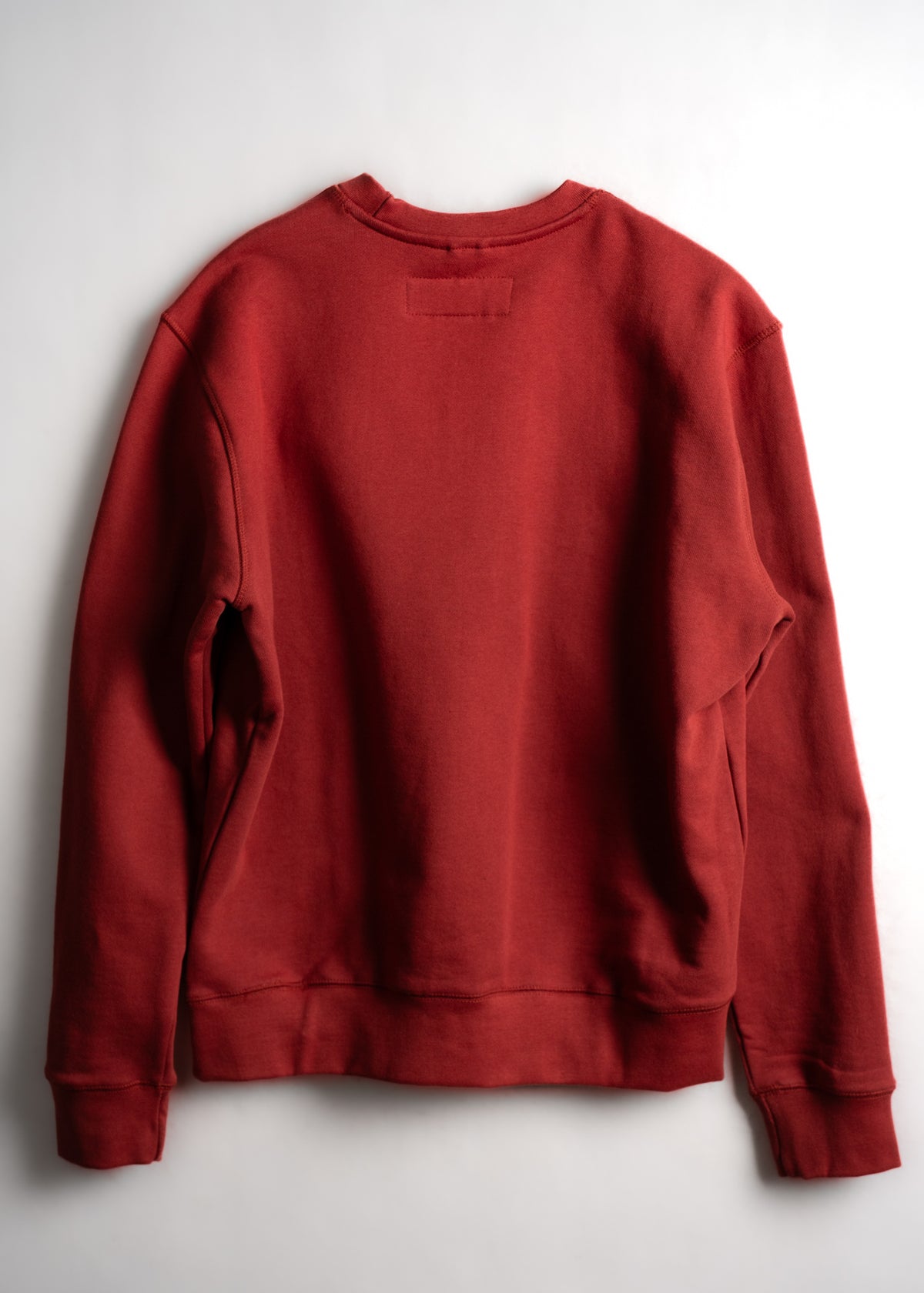 Red sweatshirt displayed on a white background, showcasing its back design and simple, casual style.