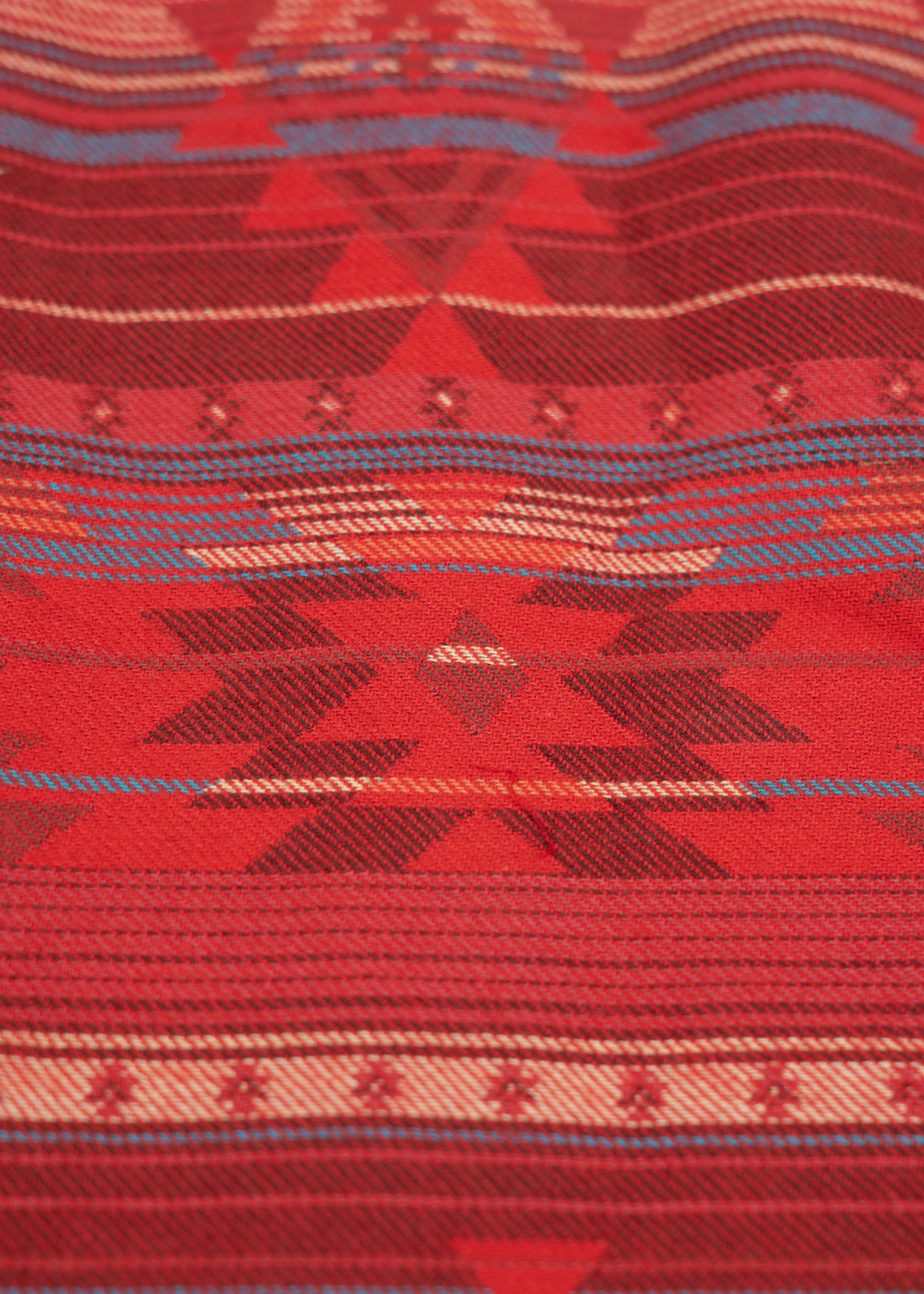 Red and blue geometric pattern on fabric, featuring triangles and stripes, creating a vibrant, textured design.