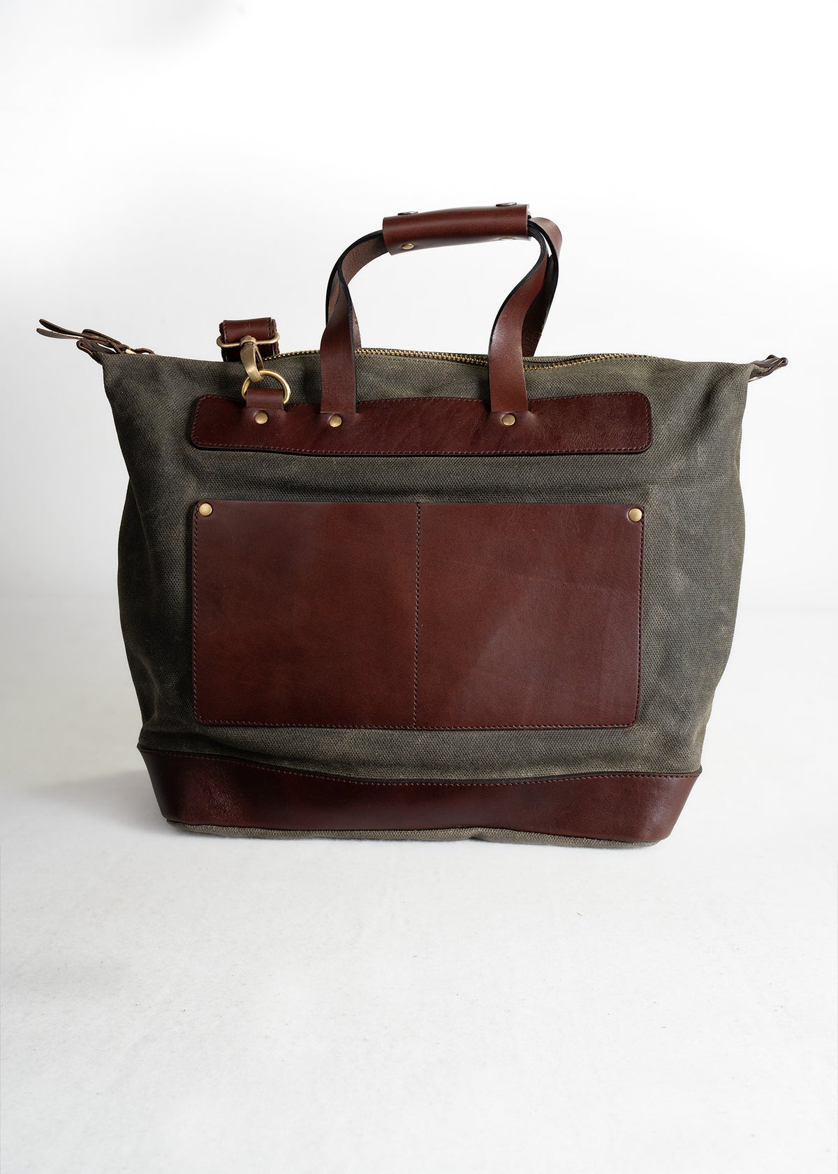 Stylish canvas tote bag with brown leather accents, featuring sturdy handles and a front pocket, set against a plain backdrop.