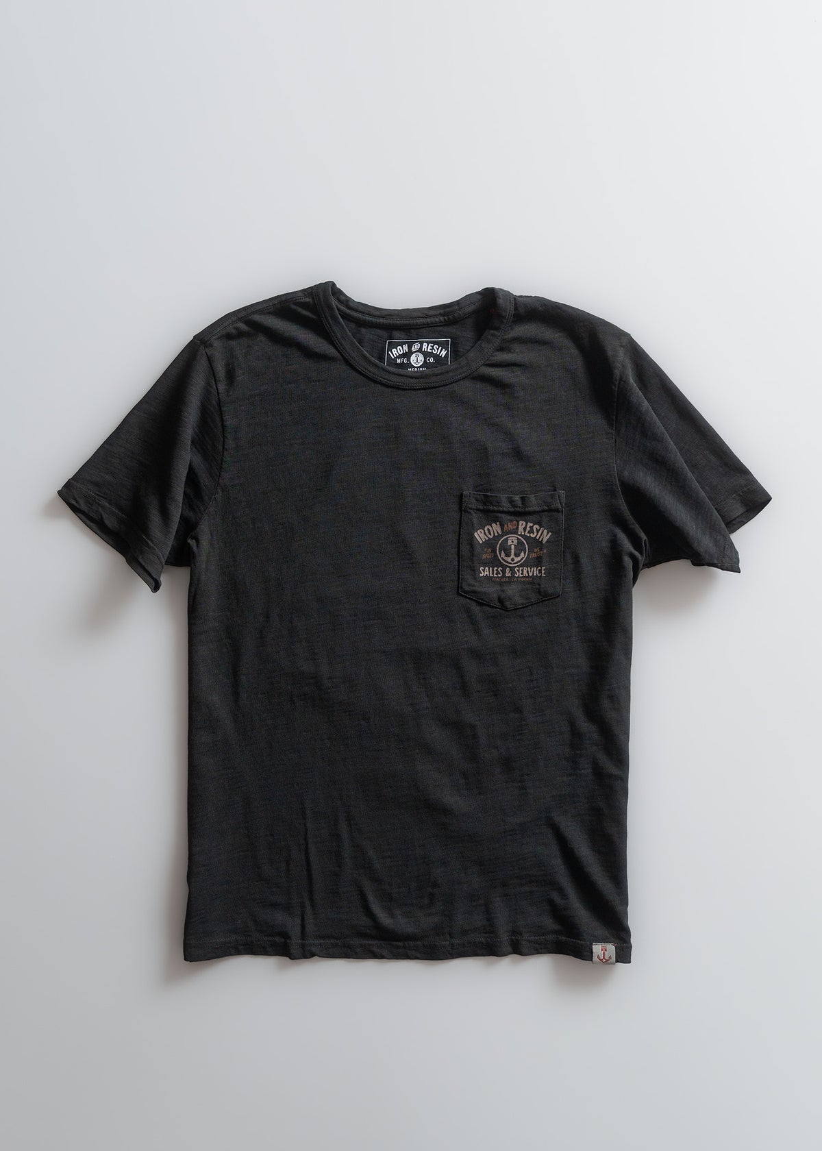 Black Iron and Resin T-shirt with a pocket design, laid flat on a white background, showcasing its simple and classic style.