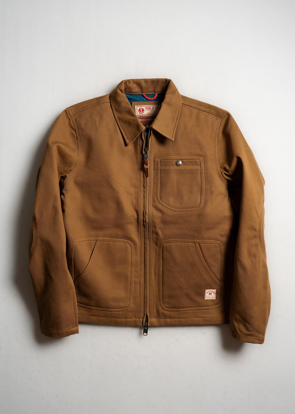 Denim fabric with a diagonal pocket and a small "Iron and Resin" label at the bottom, showcasing rugged style and craftsmanship.