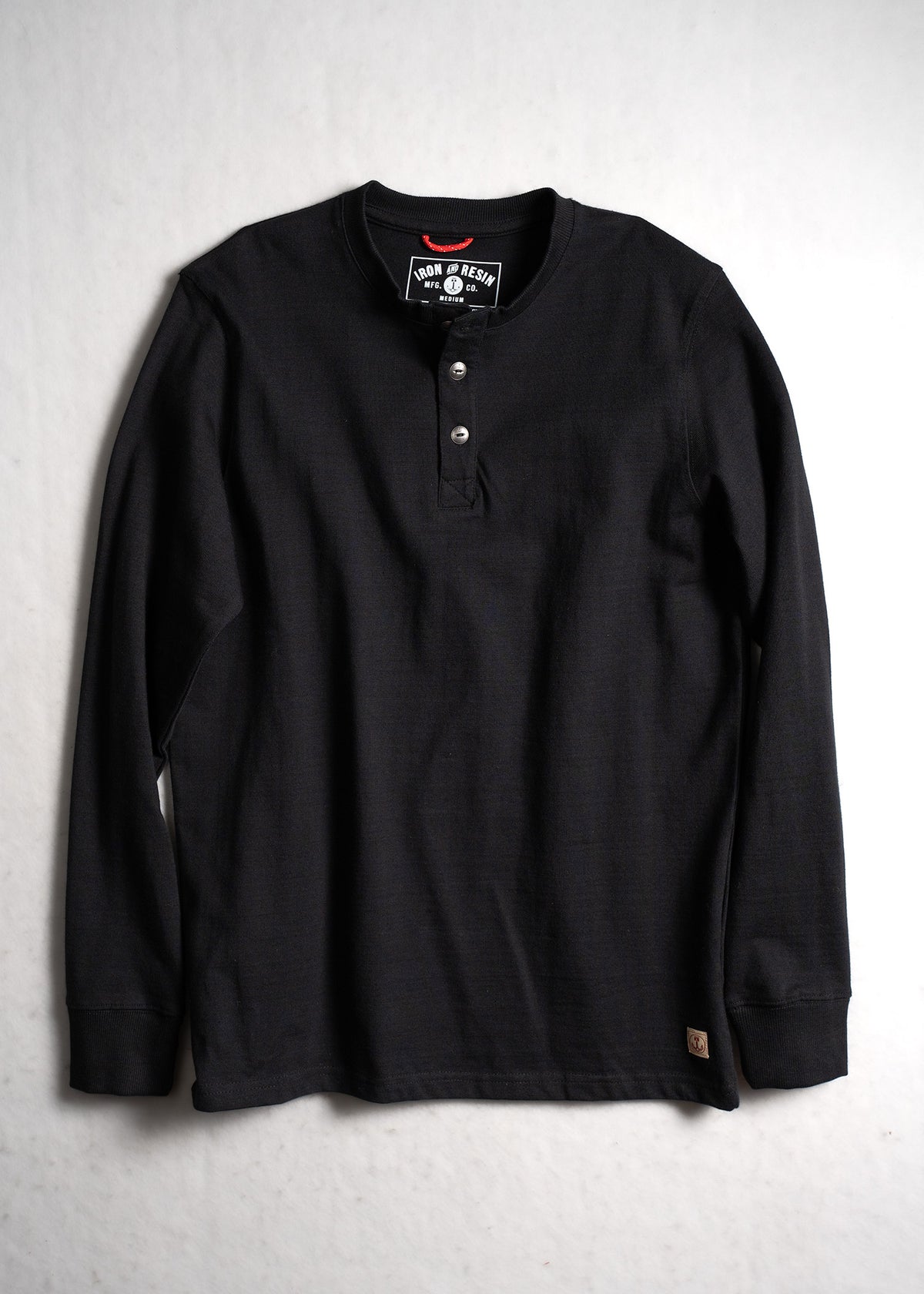 Black long-sleeve henley shirt with three buttons, laid flat on a light surface. Iron & Resin label visible inside the collar.