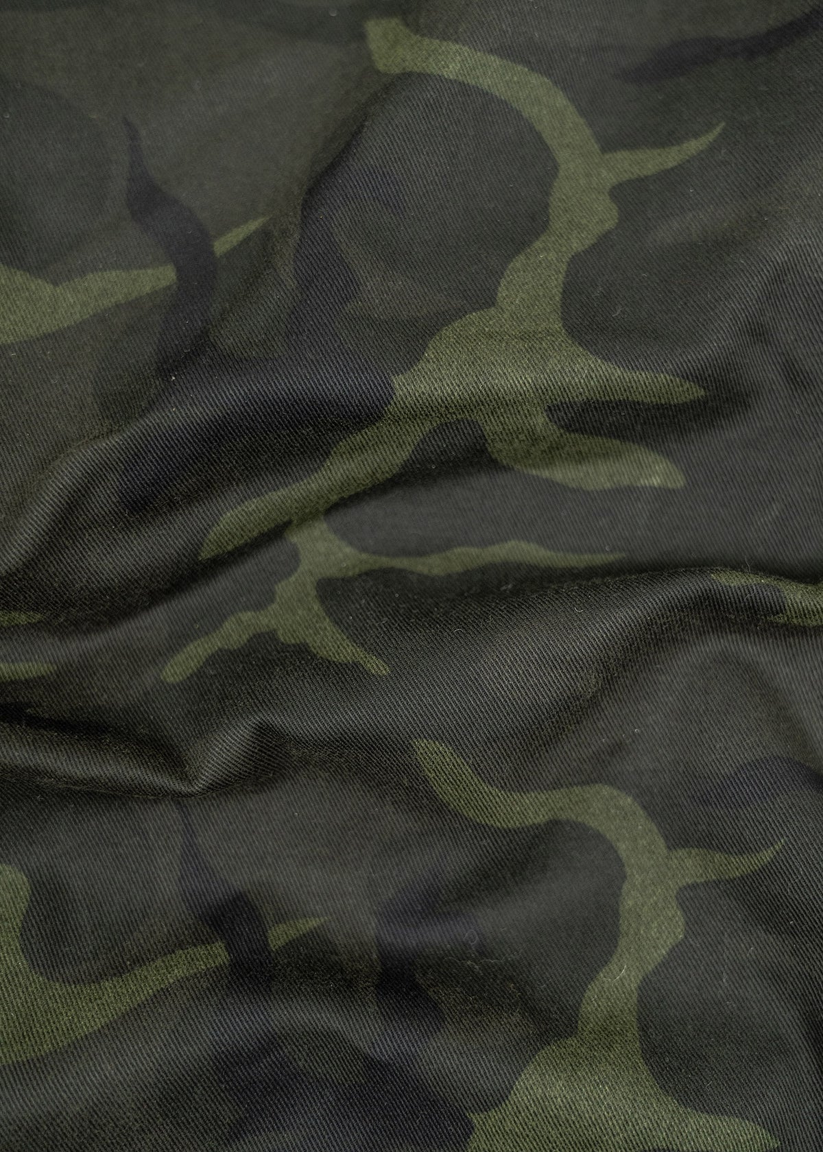 Close-up of green camouflage fabric with wavy patterns, showing texture and folds.